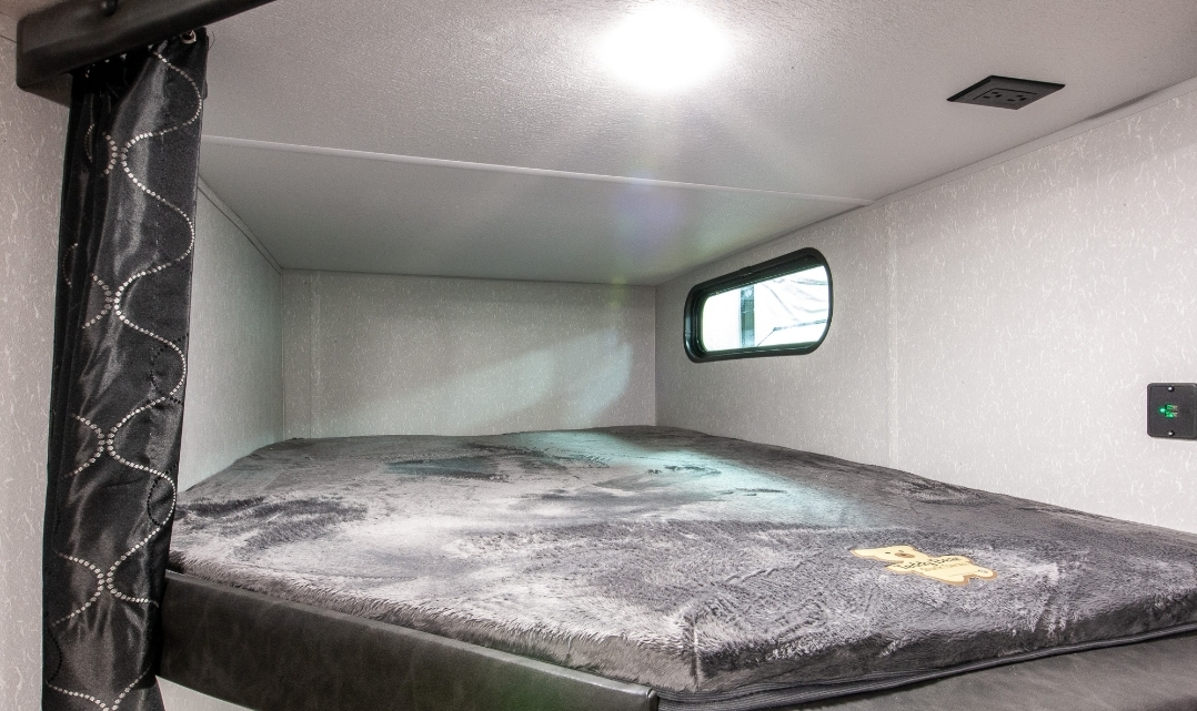 Step into this RV rental's comfy bunk bed, complete with a privacy curtain, window, and charging outlets for your adventure.. Forest River Cherokee Grey Wolf 2022