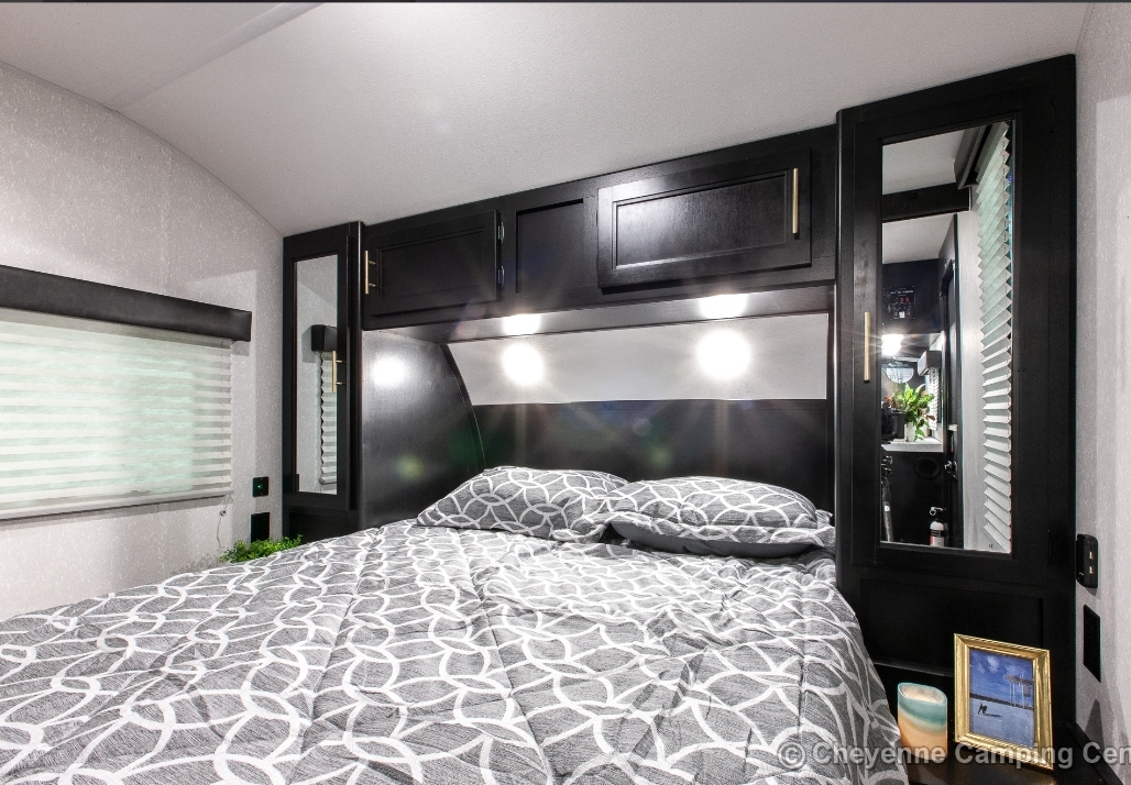 Comfortable RV rental interior showcasing a cozy bedroom with patterned bedding, modern black cabinets, and ambient lighting.. Forest River Cherokee Grey Wolf 2022