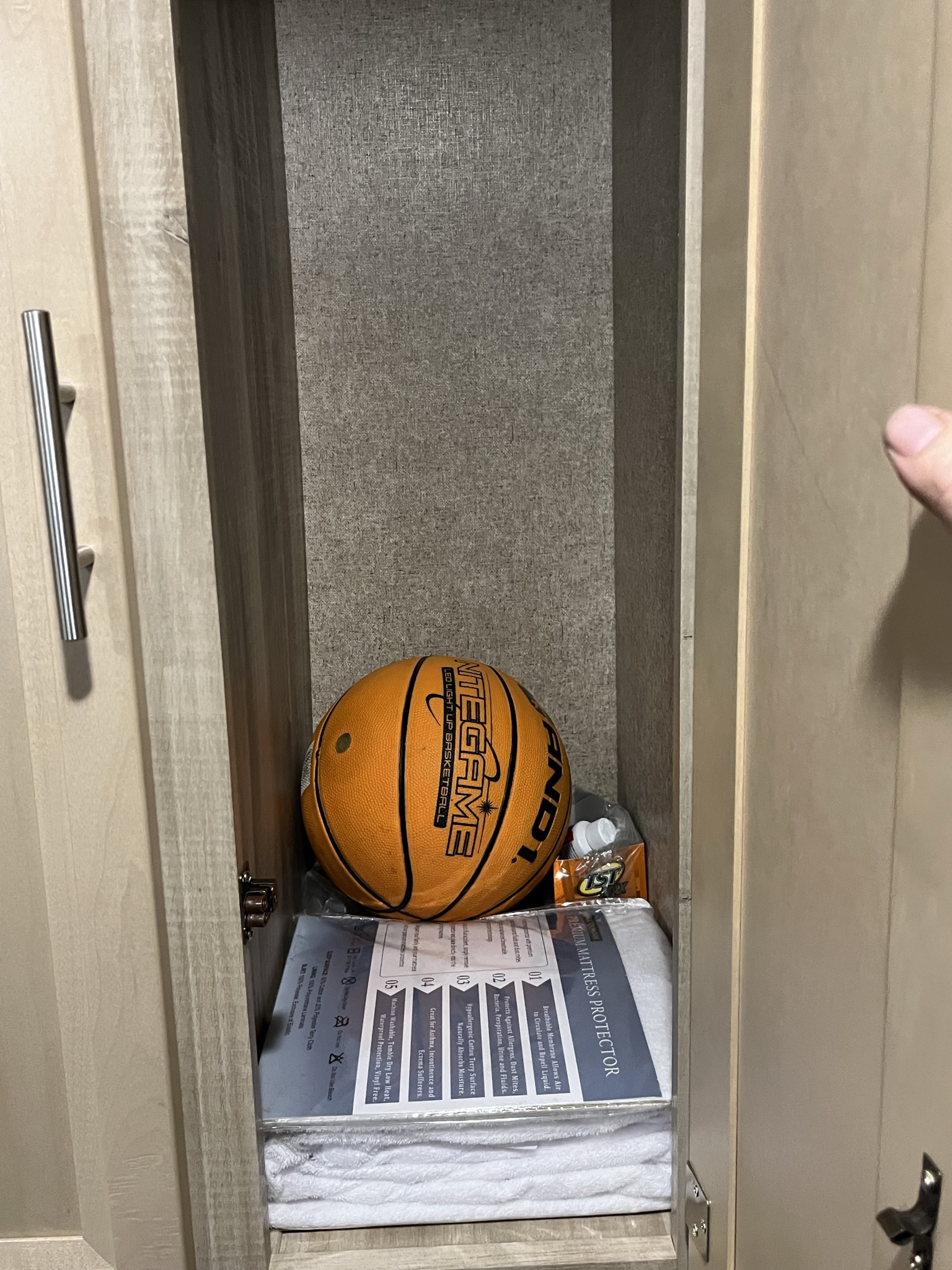 Inside an RV rental cabinet, an AND1 LED basketball rests on a premium mattress protector and towels, ready for adventure.. Forest River Coachmen Catalina SBX 2019