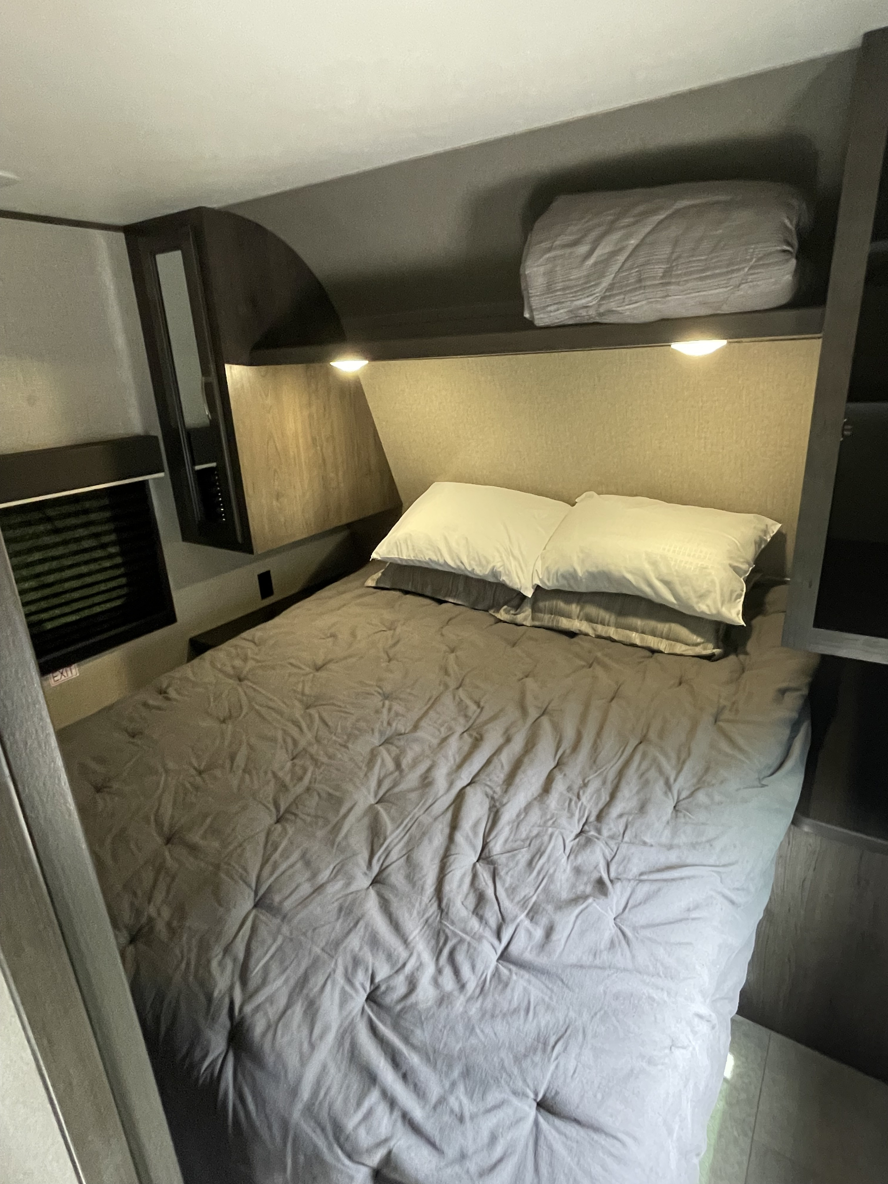 Cozy RV rental bedroom features a gray bed, white pillows, reading lights, and overhead storage.. Jayco Jay Flight SLX 2021