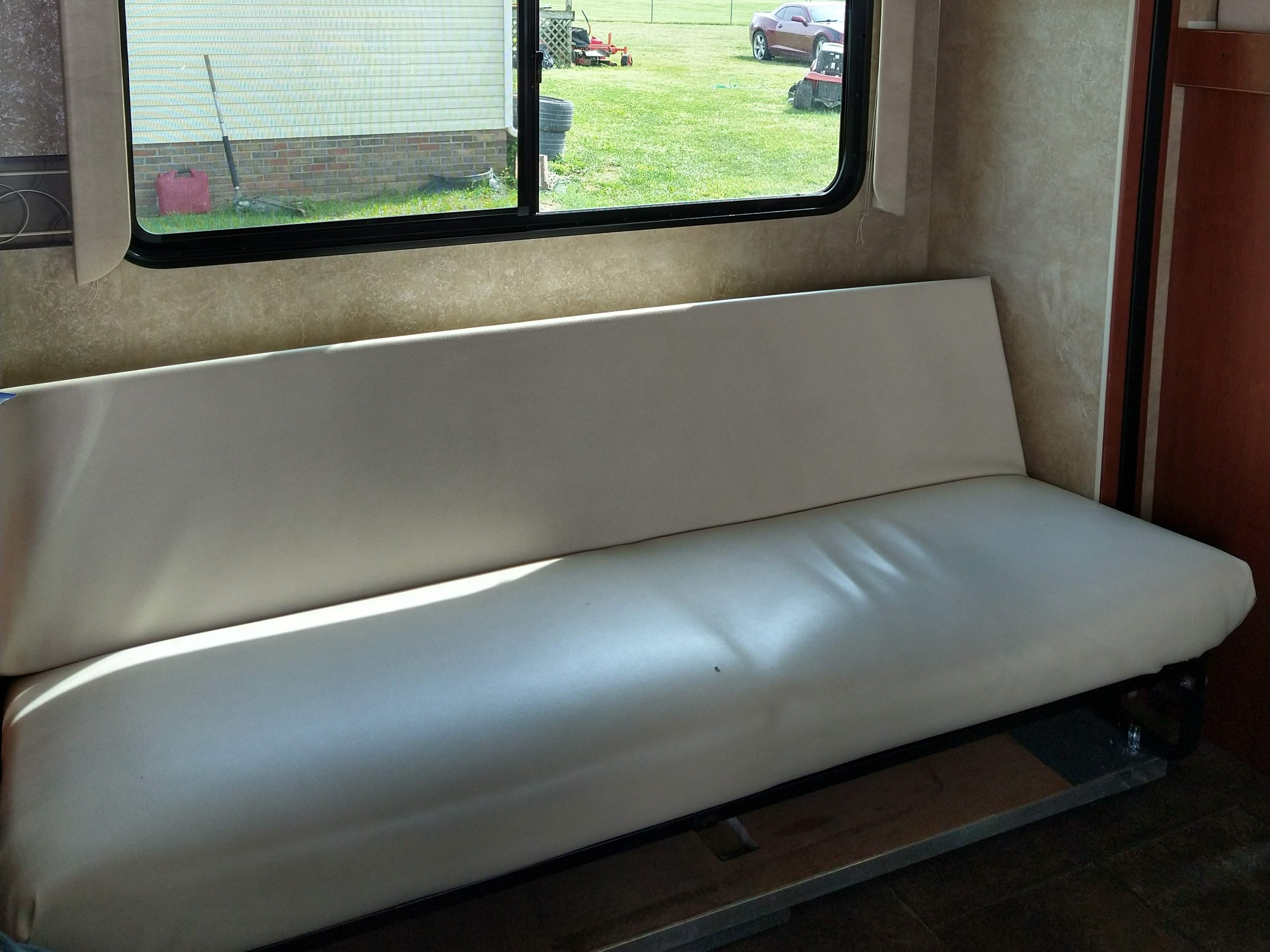 RV interior: A light-colored sofa/bed offers comfort, with a large window view of a grassy yard. Perfect for your RV rental.. Winnebago Minnie Winnie 2015