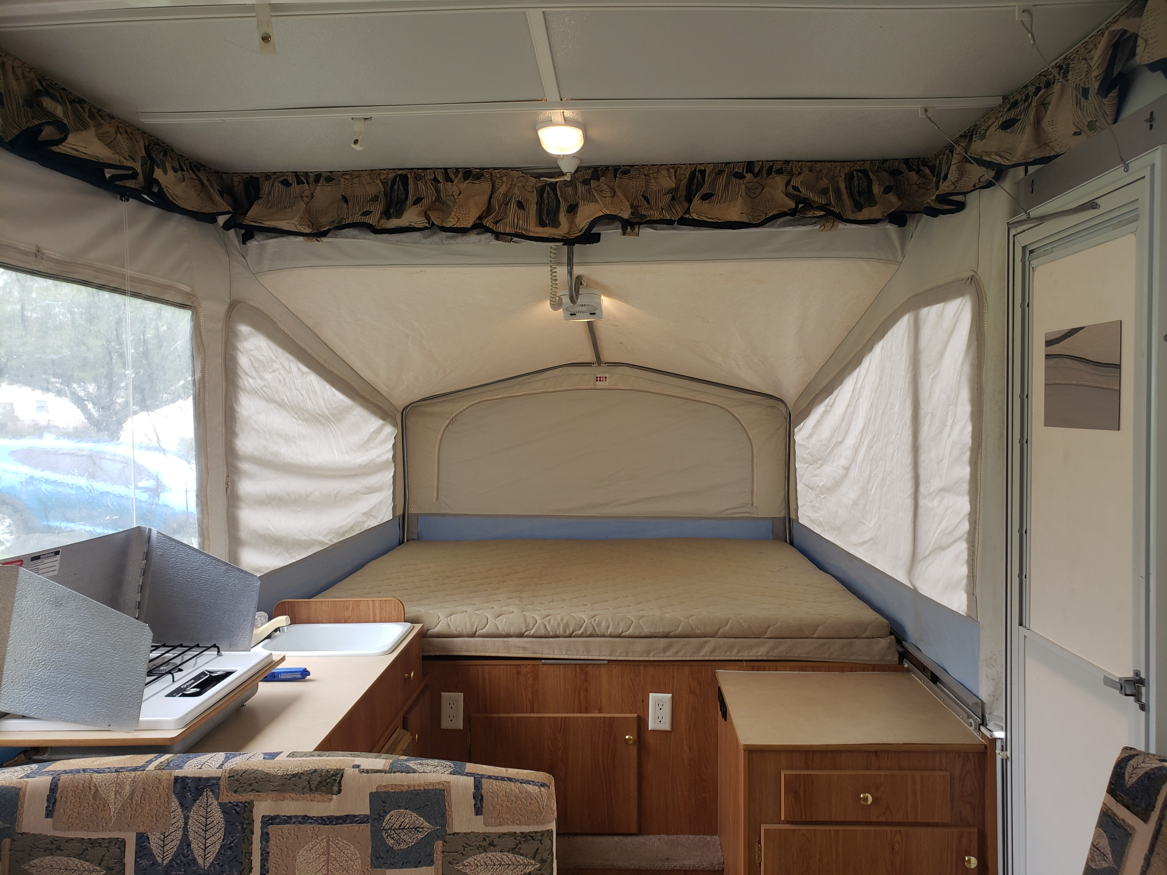 Inside an rv rental pop-up camper: a large bed, cozy dining nook, and compact kitchen are ready for adventure.. Jayco Select 2006