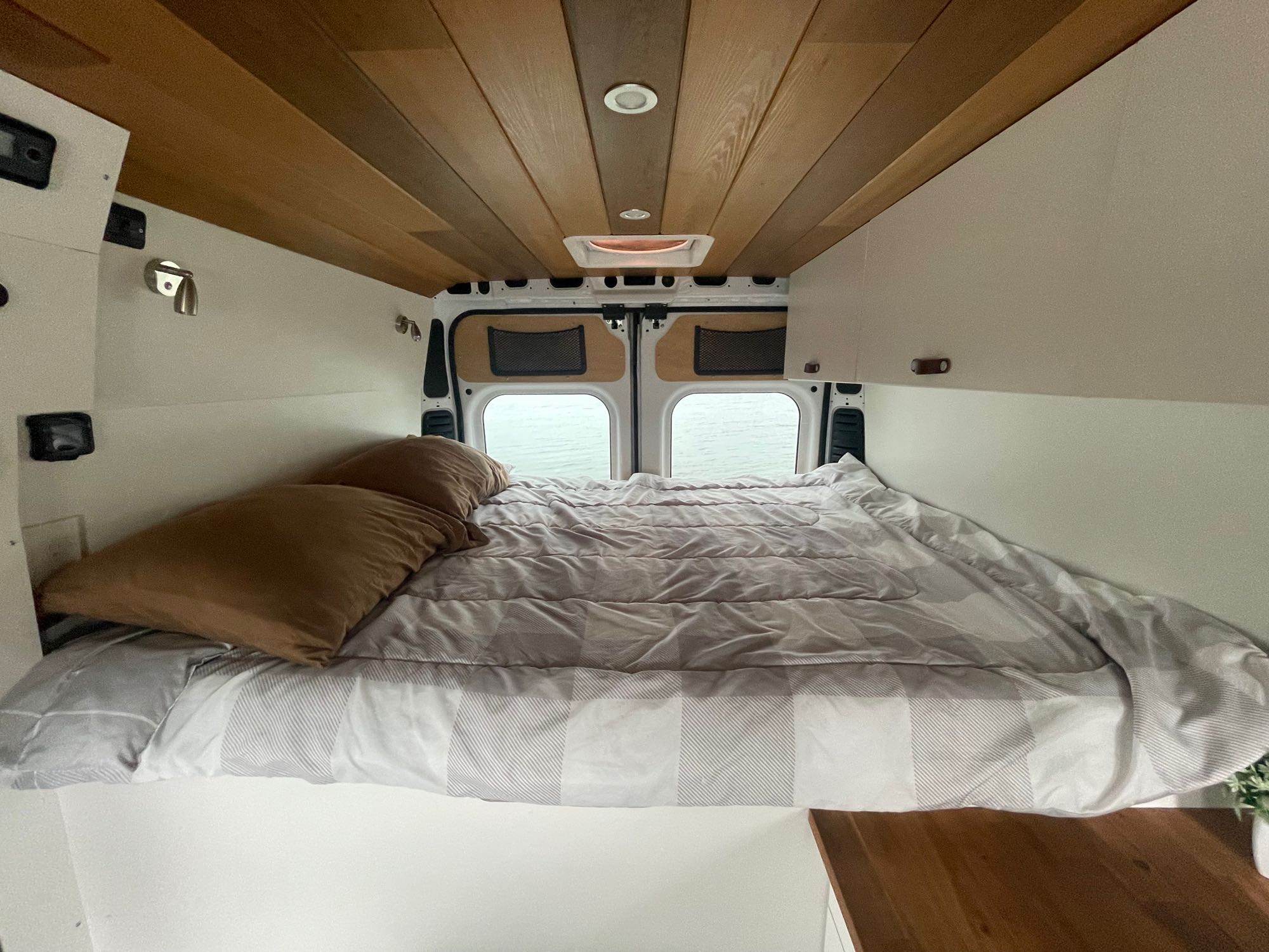 Cozy RV rental interior with a comfortable bed, wood-paneled ceiling, and scenic water view from rear windows.. Other Other 2019