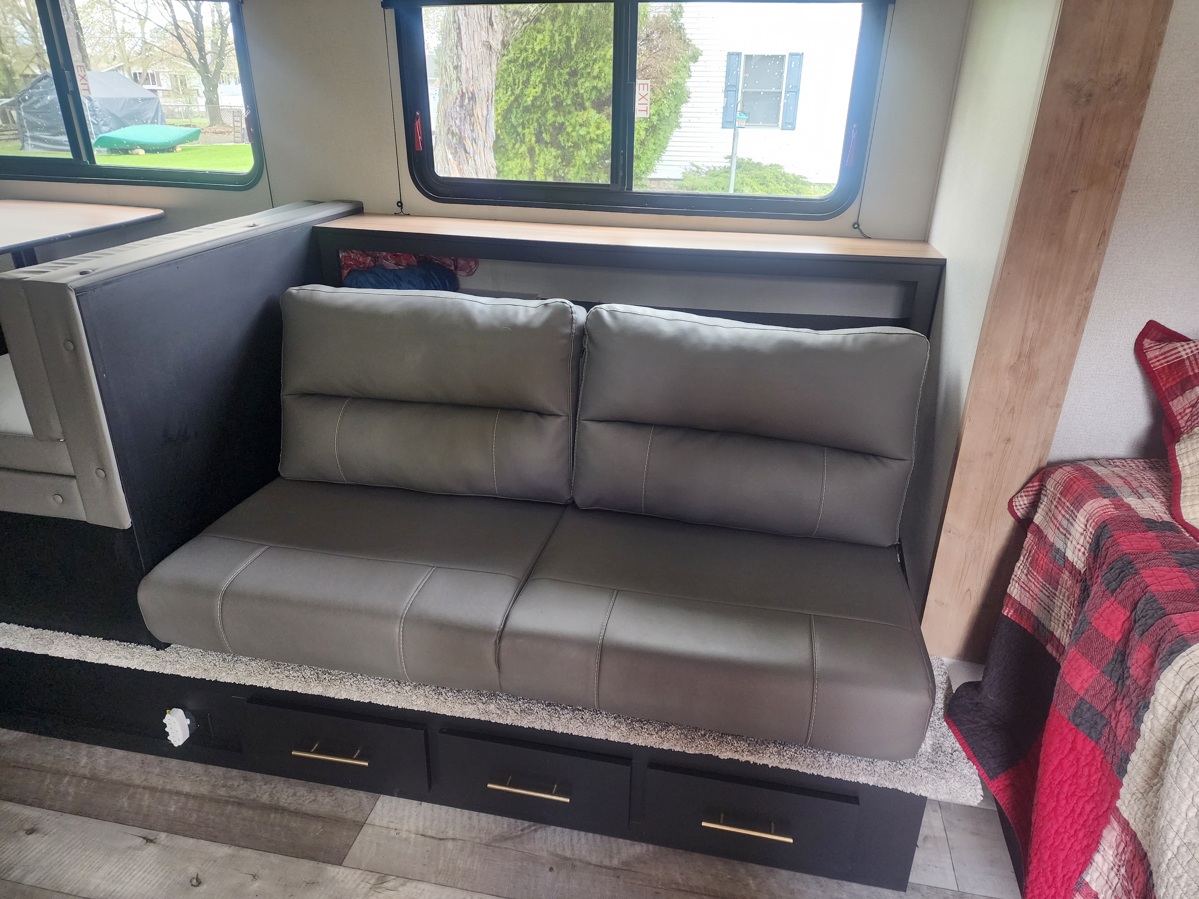 Spacious RV rental interior with comfy gray seating, built-in storage, and scenic views from large windows. Ideal for travel.. Keystone RV Springdale 2022