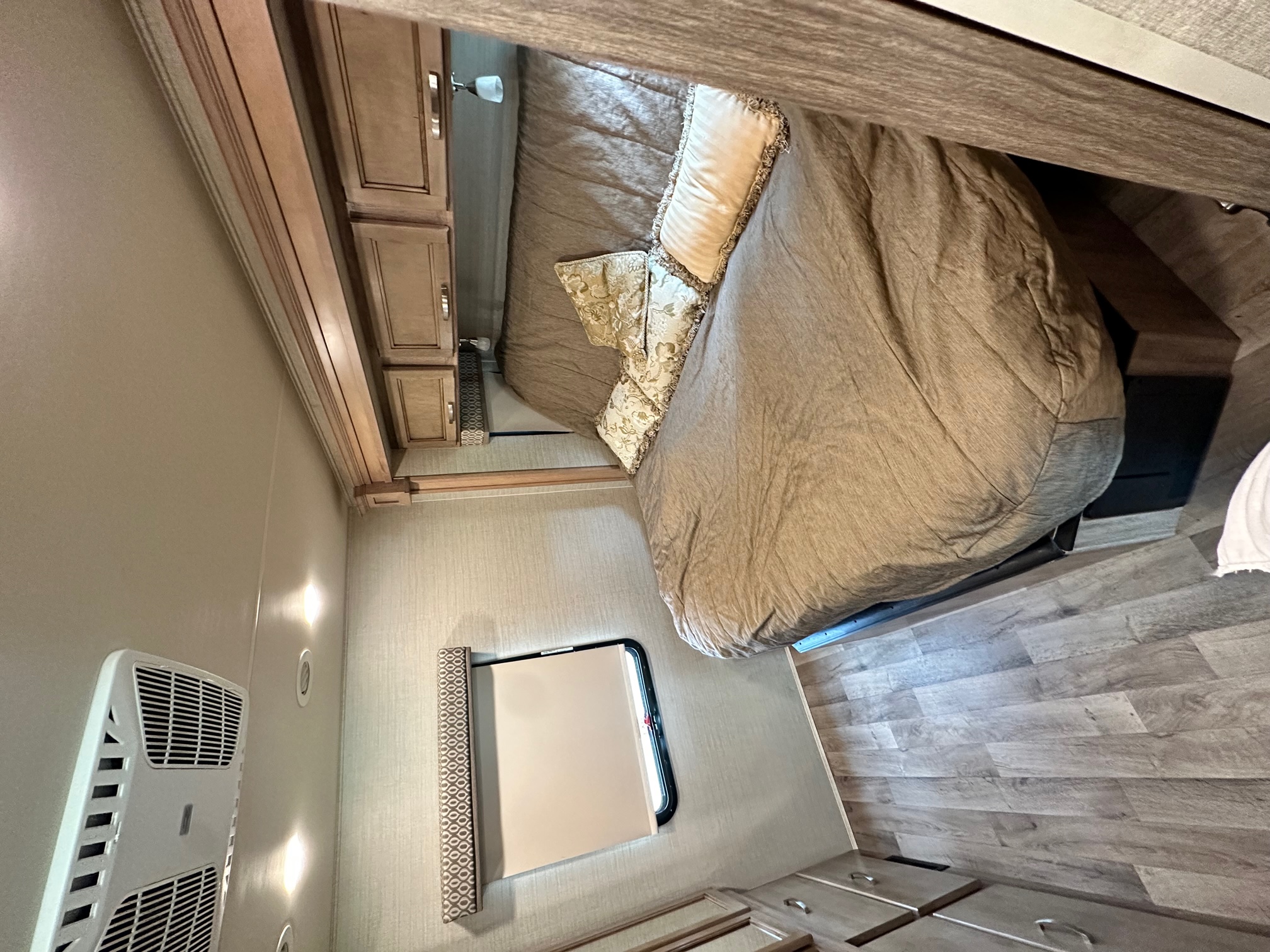 Inside an RV rental: a well-appointed bedroom with a comfy bed, warm lighting, and wood-look floors.. Jayco Precept 2019