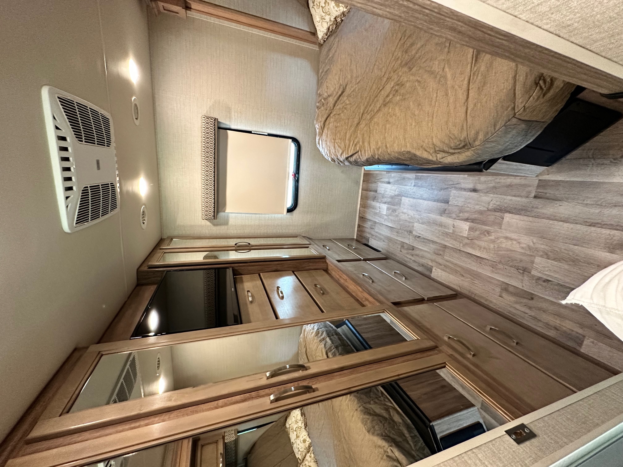 Spacious RV rental bedroom showcasing a comfortable bed, built-in storage, TV, and air conditioning for ultimate comfort.. Jayco Precept 2019