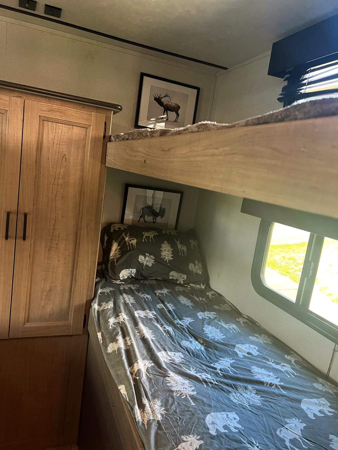 Cozy RV rental bunk beds with nature-themed bedding and animal art. Ideal for family travel adventures.. Keystone RV Hideout Luxury 2021