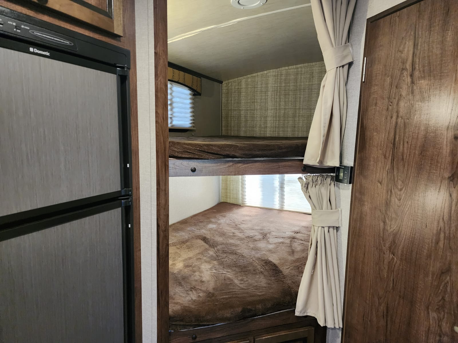 RV rental interior: Cozy bunk beds with privacy curtains, window, and a Dometic refrigerator.. Cruiser RV MPG Ultra Lite 2017