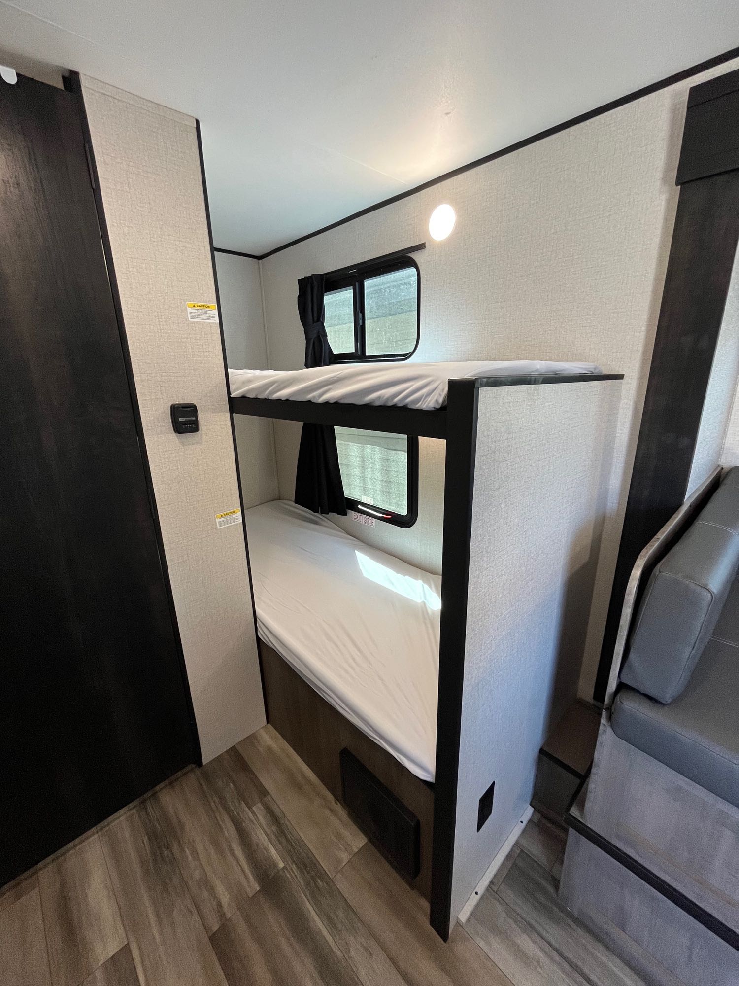 Cozy RV rental interior with built-in bunk beds, each featuring a window and white bedding, perfect for family adventures.. Open Range 180BHS 2022