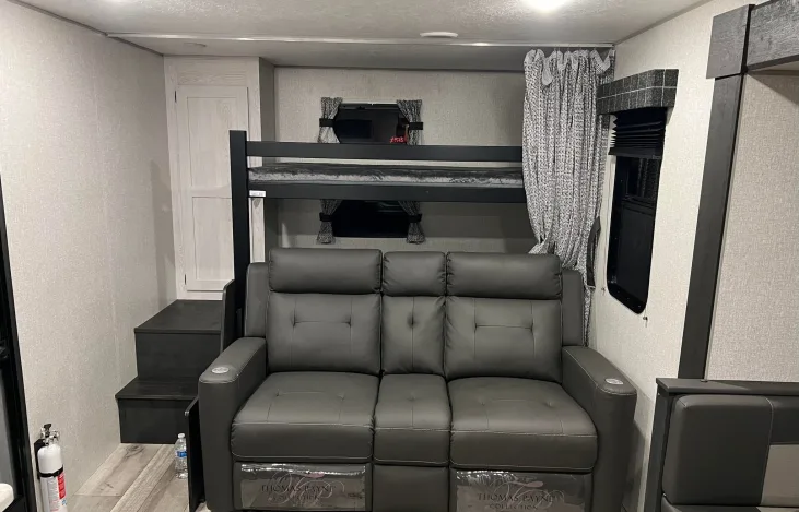 Comfortable RV rental interior featuring a reclining sofa and bunk beds, perfect for family travel.. Sportsmen SE 2022