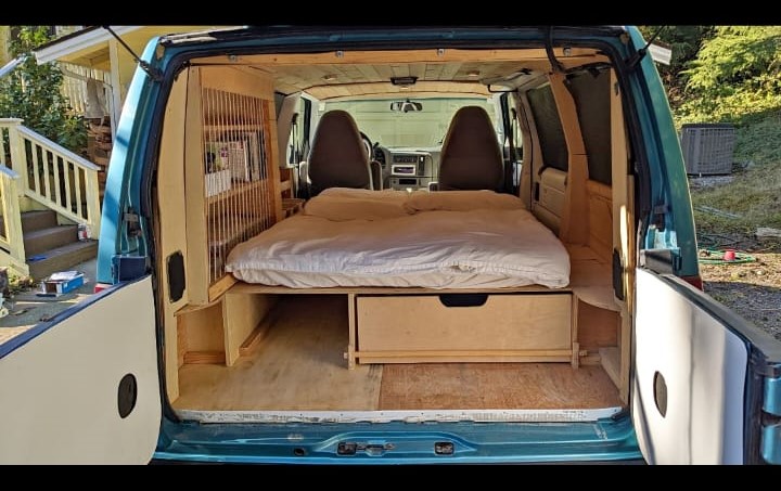 Experience comfort in this camper van rv rental! Features a built-in bed, under-bed storage, and warm wood interior.. Chevrolet Other 1996