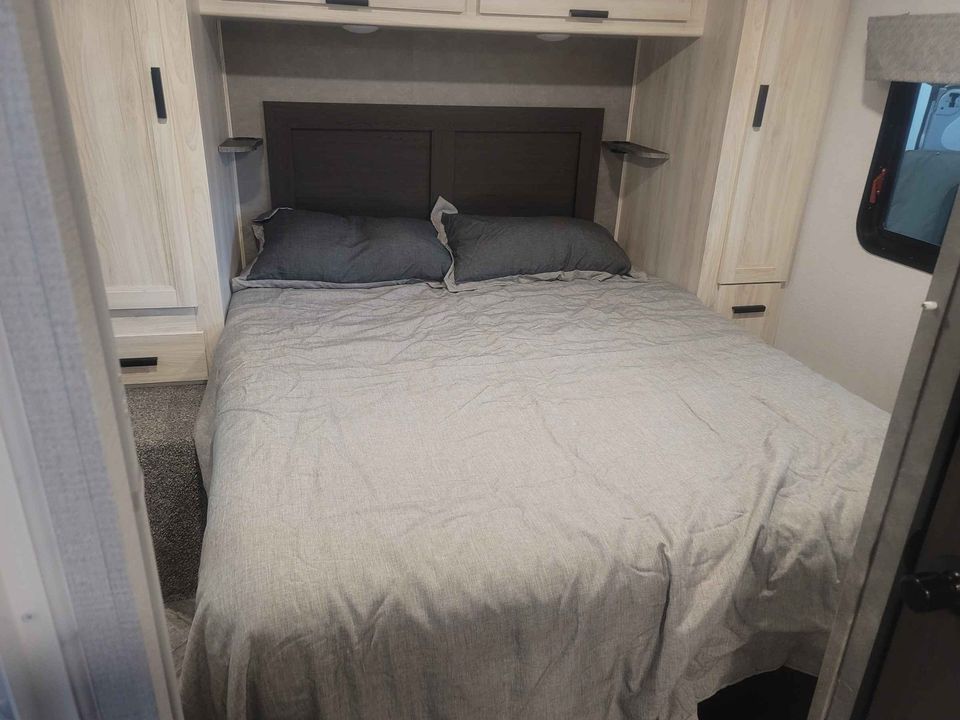 Cozy RV rental bedroom with a large bed, built-in side cabinets, and overhead storage for a great trip.. Forester LE 2022