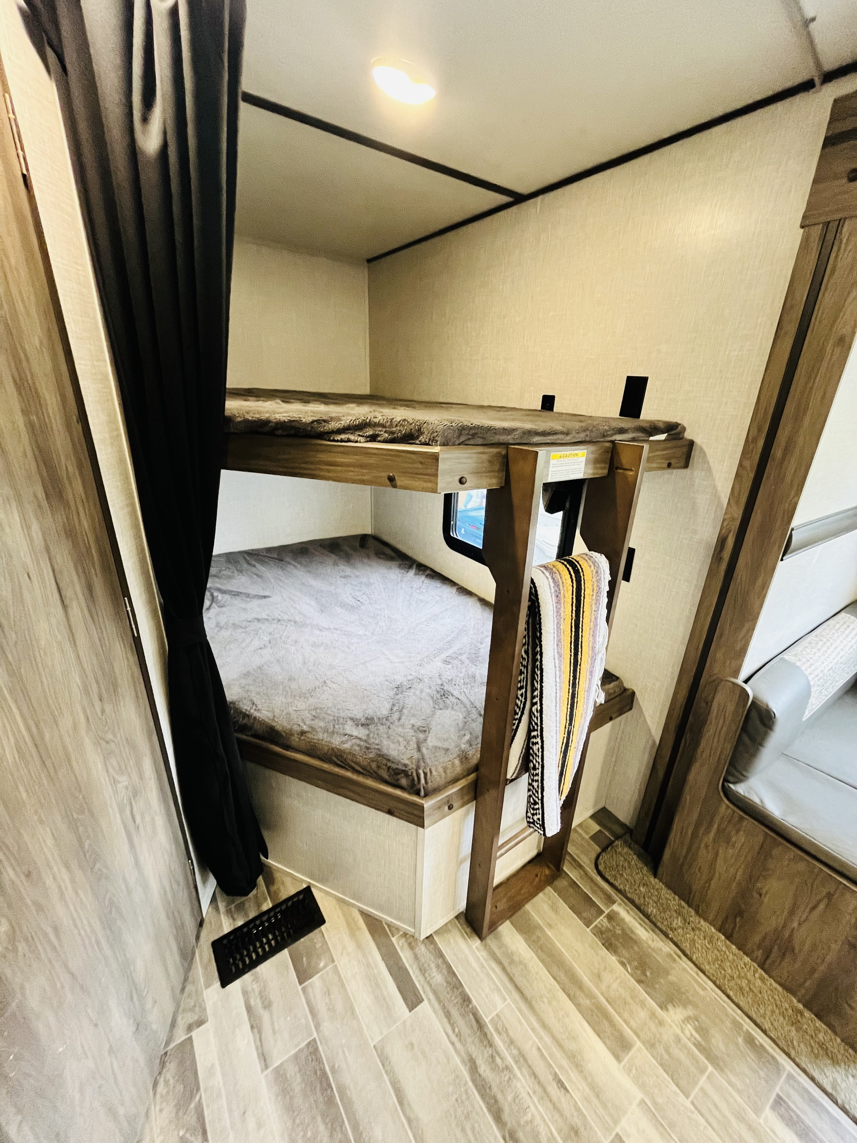 RV rental bunk beds: Features include a top bunk with fluffy blanket, lower bunk, privacy curtain, and bright ceiling light.. Crossroads RV Zinger Lite 2022