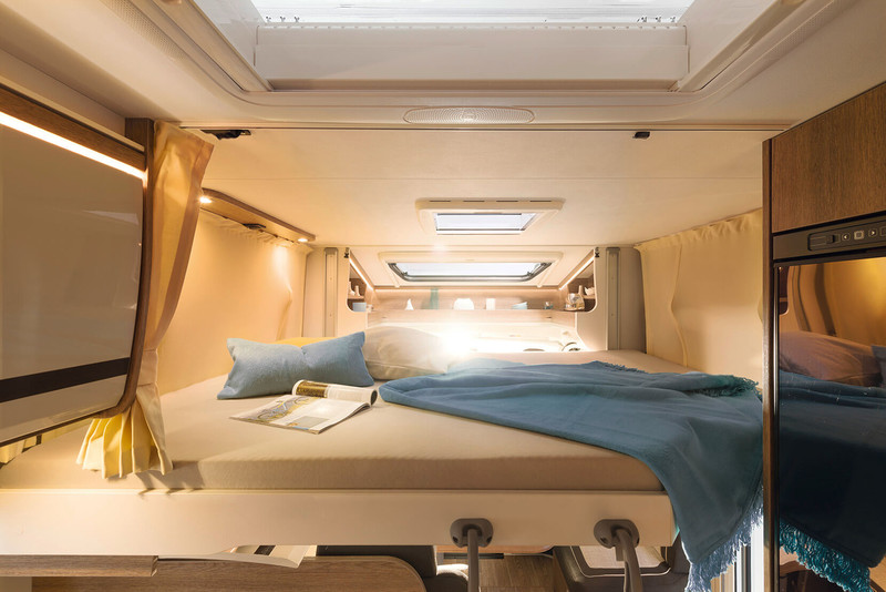 Cozy RV bedroom featuring a large, illuminated bed, skylights, and storage. Perfect for your next RV rental adventure.. Dethleffs TREND 90 T 7057 DBM 2023