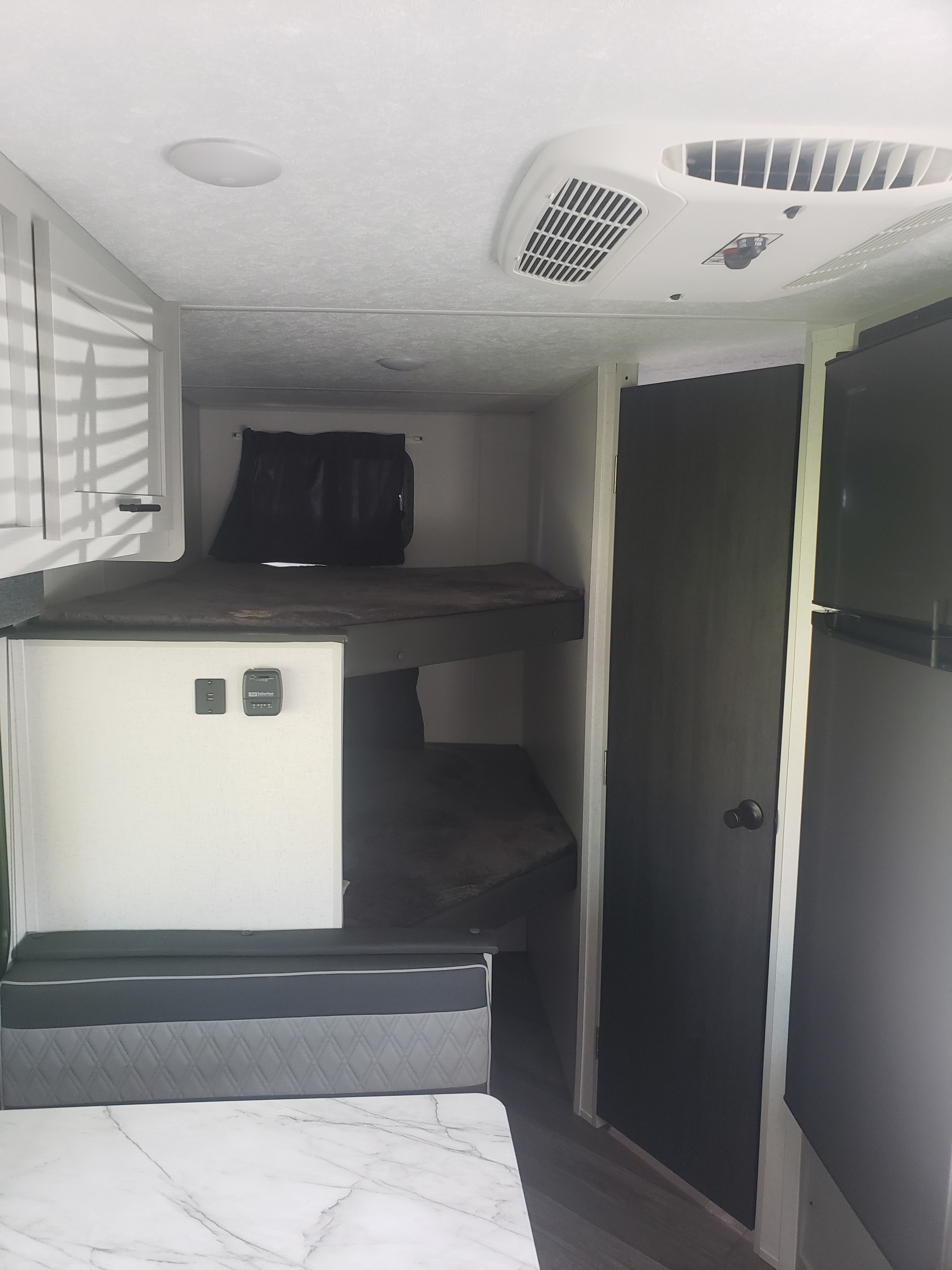 RV rental interior with bunk beds, dinette, fridge, and AC controls. Cozy and functional space for trips.. Forest River Wildwood FSX 2022