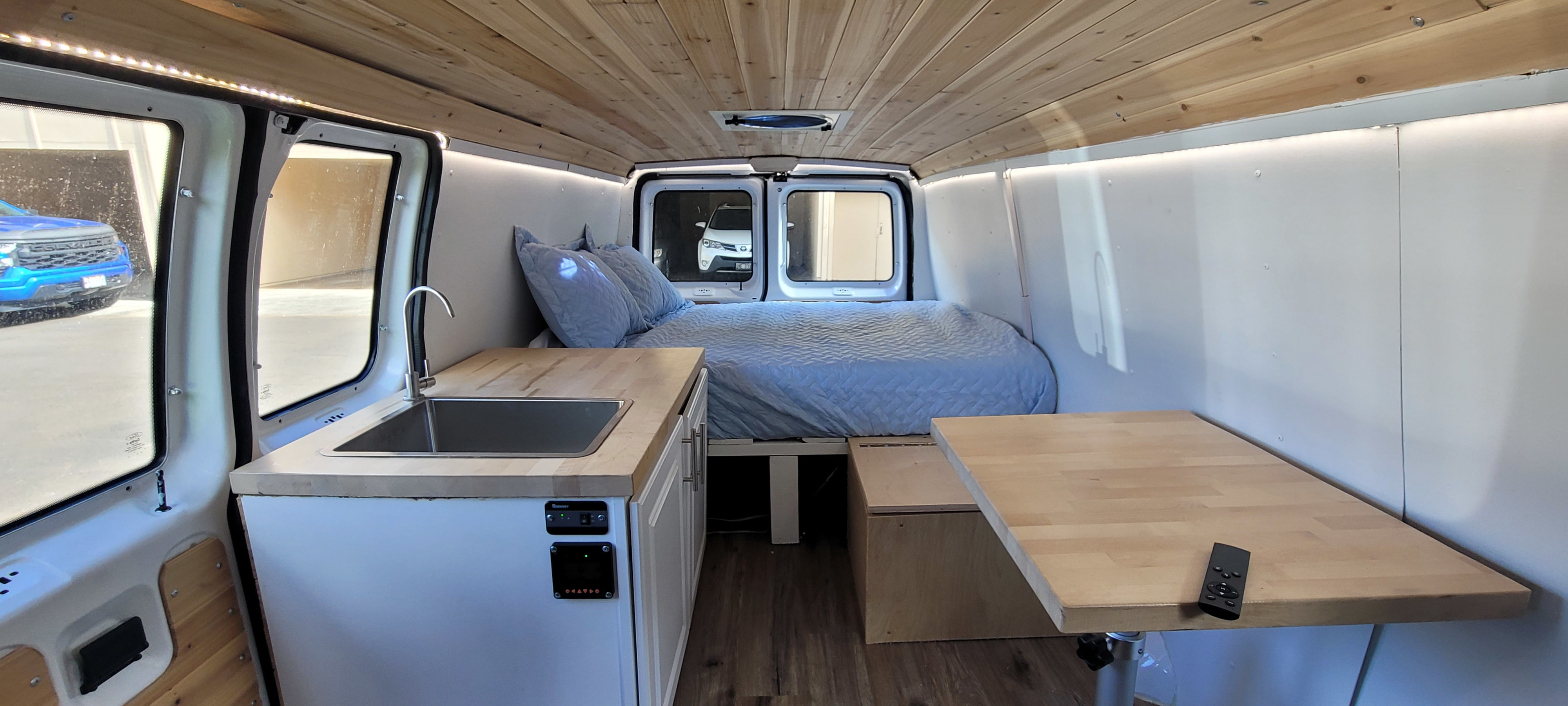 Spacious RV rental interior with a cozy bed, kitchen sink, and dining table, perfect for your next adventure.. Ford E250 2012