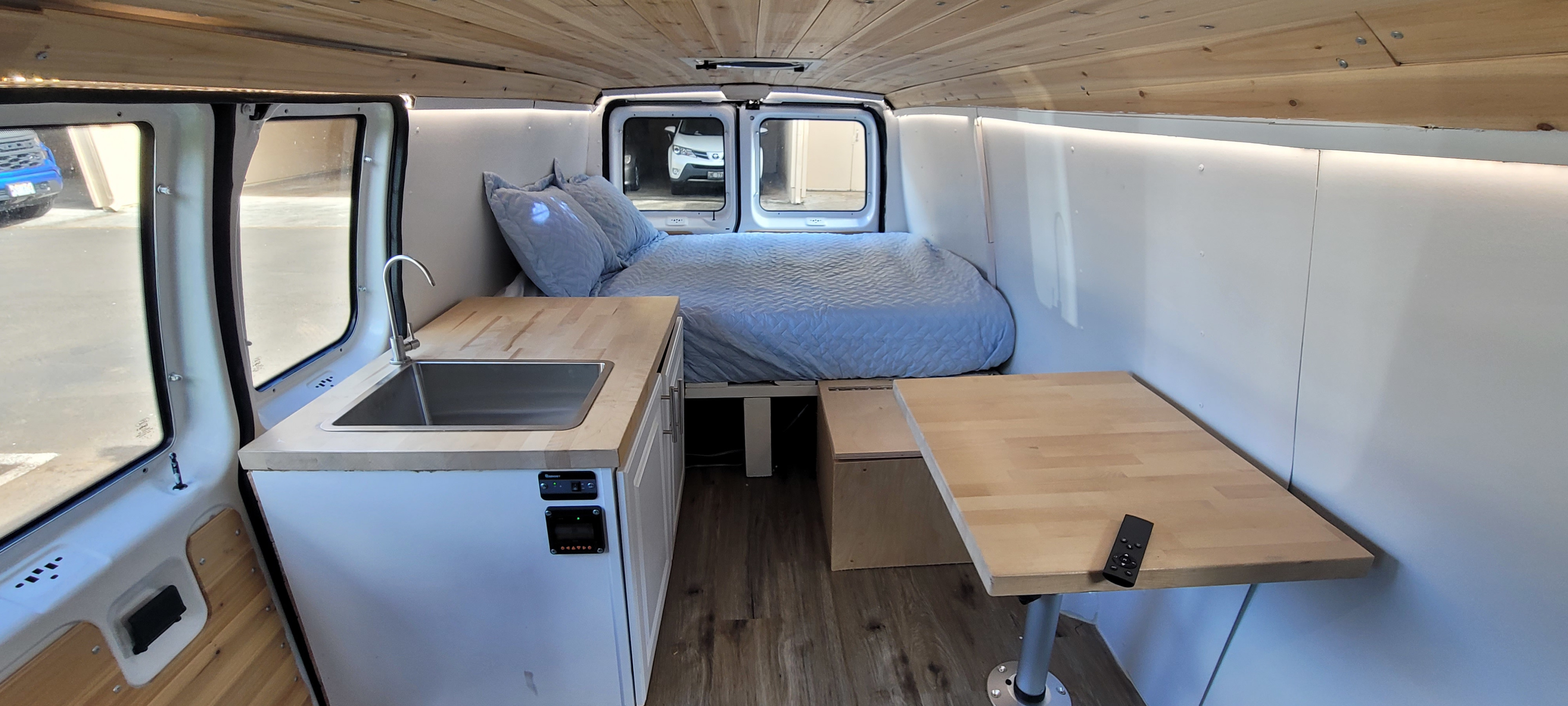 This RV rental's van conversion offers a bright interior with a built-in kitchen, bed, and adjustable table.. Ford E250 2012