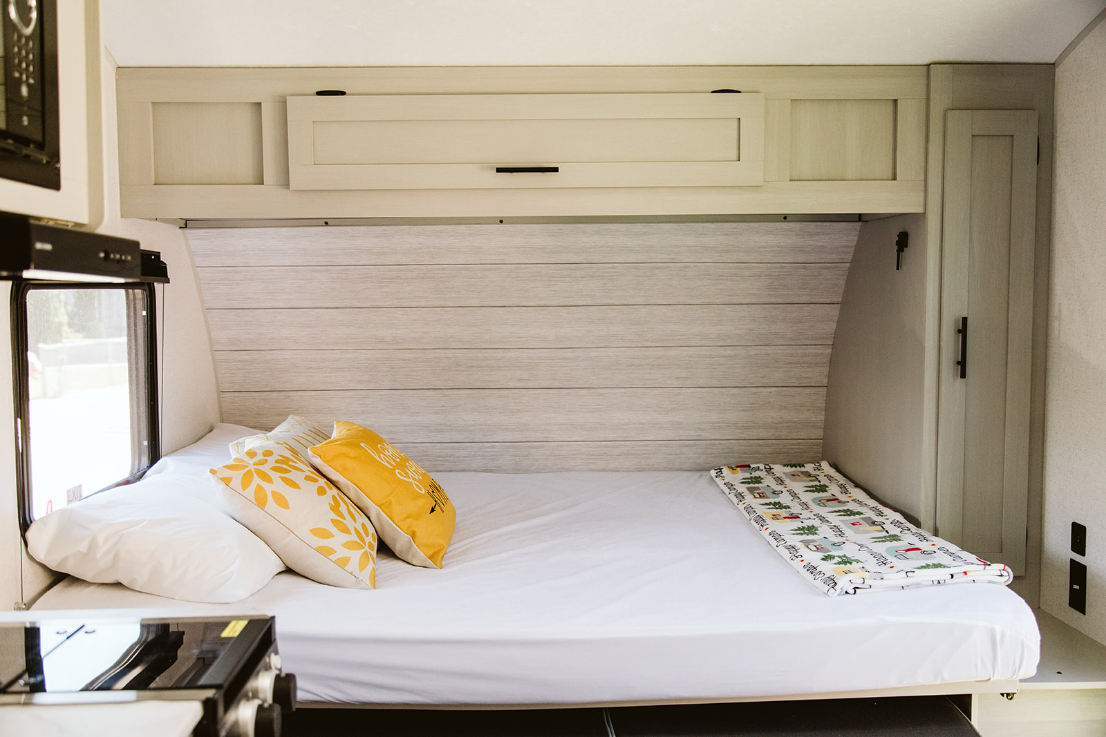 This RV rental's sleeping area features a cozy bed with white sheets, yellow pillows, and an adorable camping blanket.. Forest River Salem FSX 2022