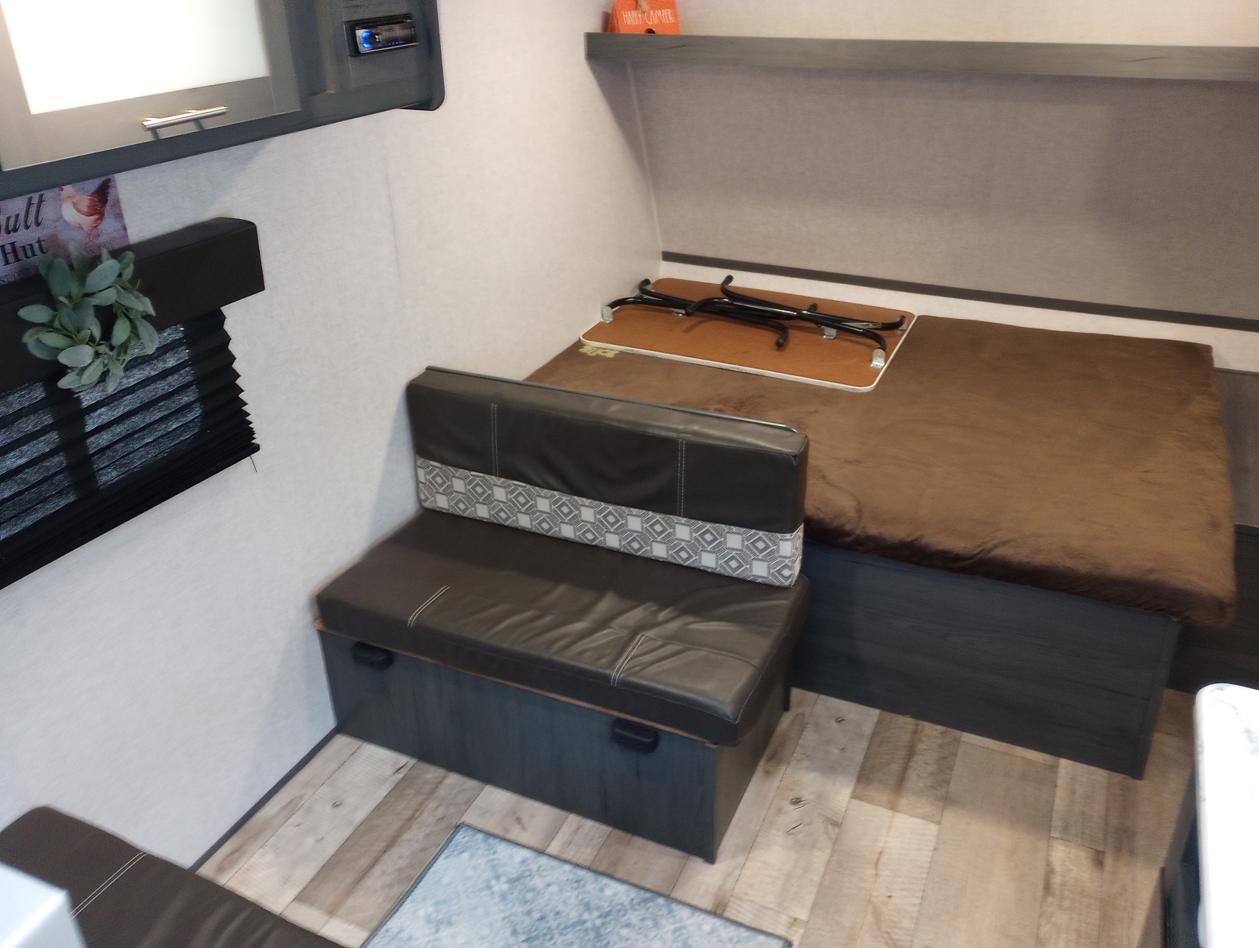 This RV rental interior offers a dark dinette with under-seat storage and a brown bed. A compact, functional living space.. Dutchmen 17BH 2021