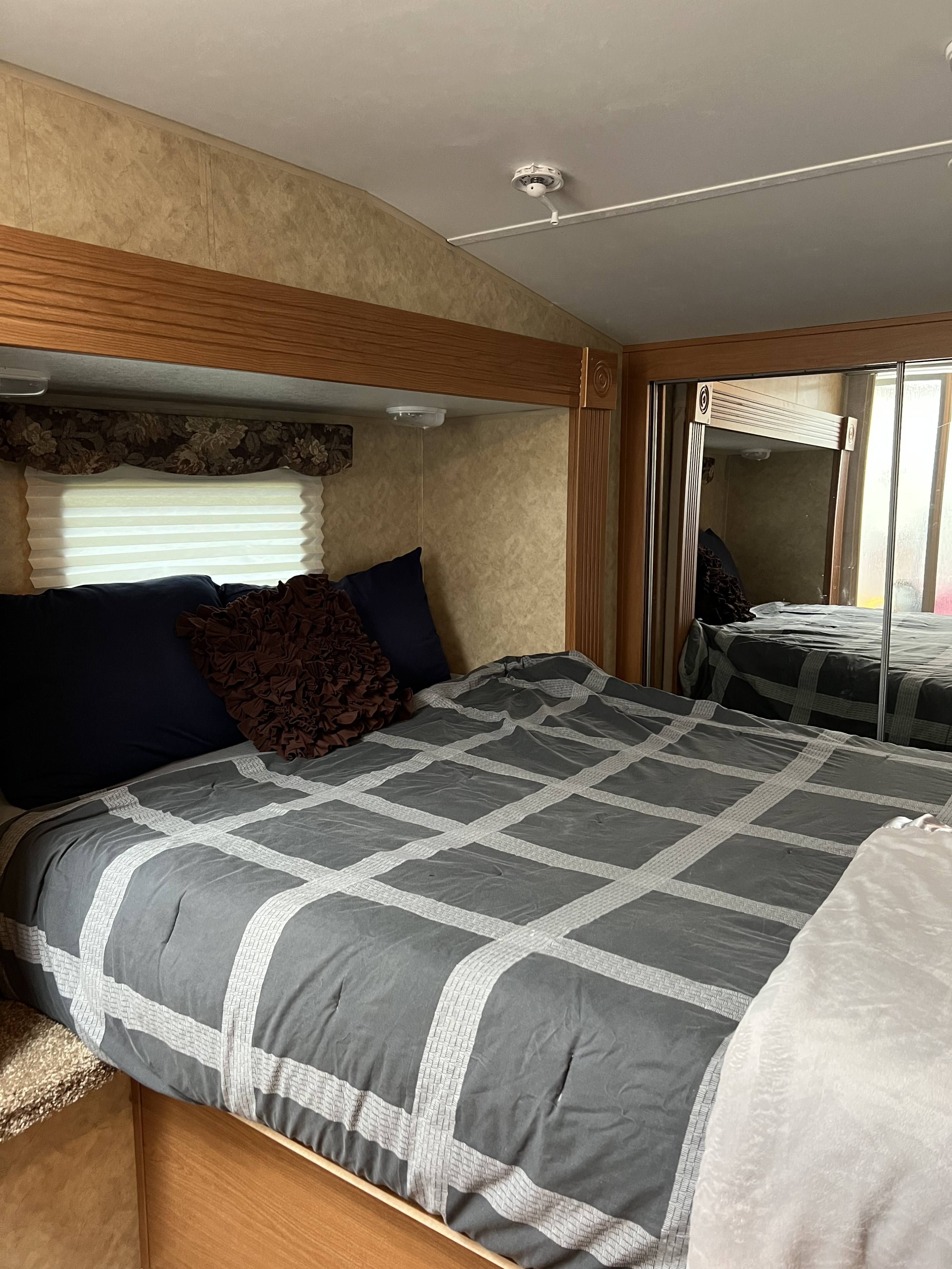 Relax in this cozy RV rental bedroom. Features include a comfy bed with a gray comforter, soft pillows, and mirrored closet.. Denali Denali Fifth Wheel 2011