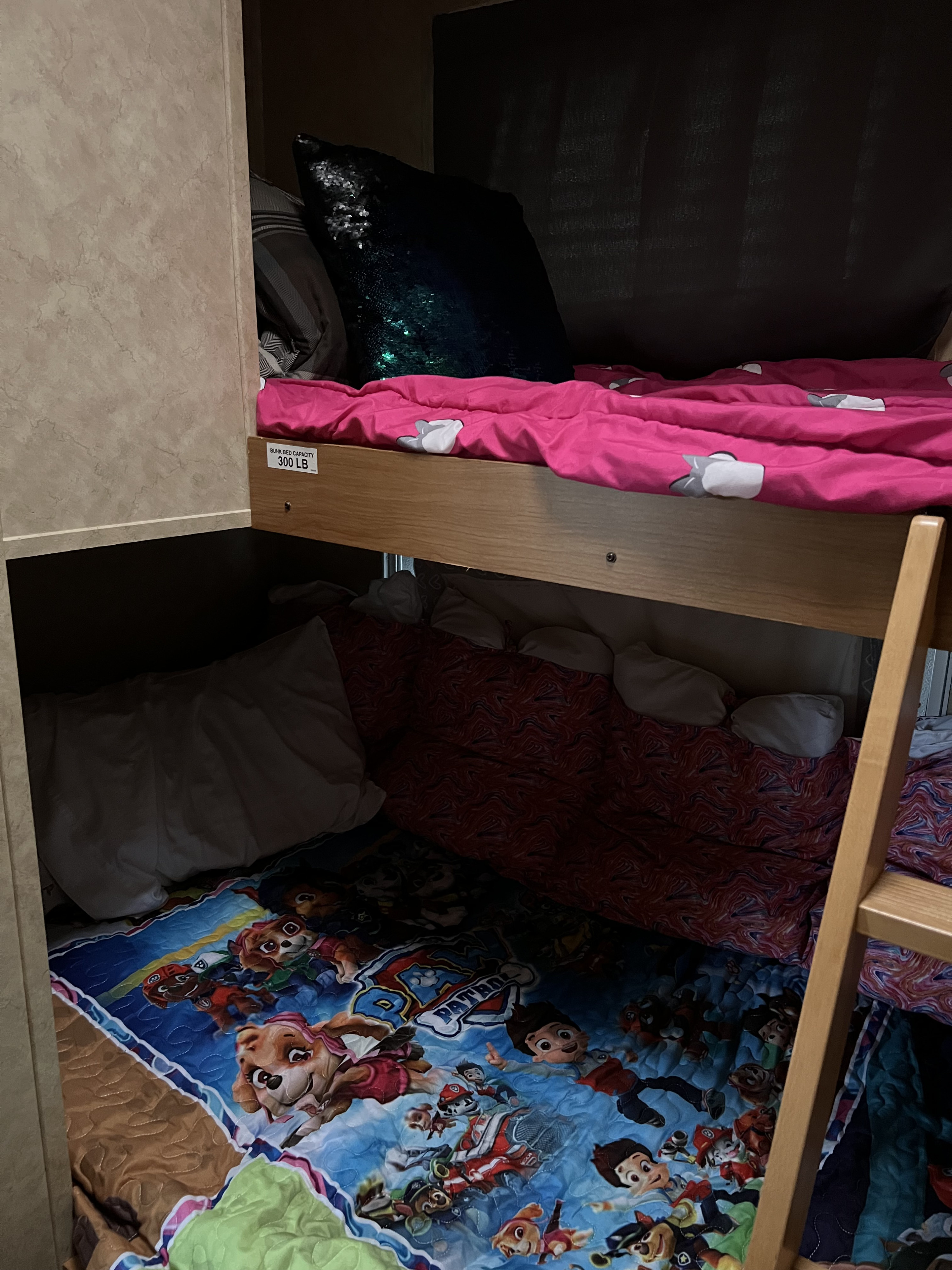 An RV rental's bunk beds: pink comforter on top, Paw Patrol blanket below. Max 300lb capacity for safe travel.. Denali Denali Fifth Wheel 2011