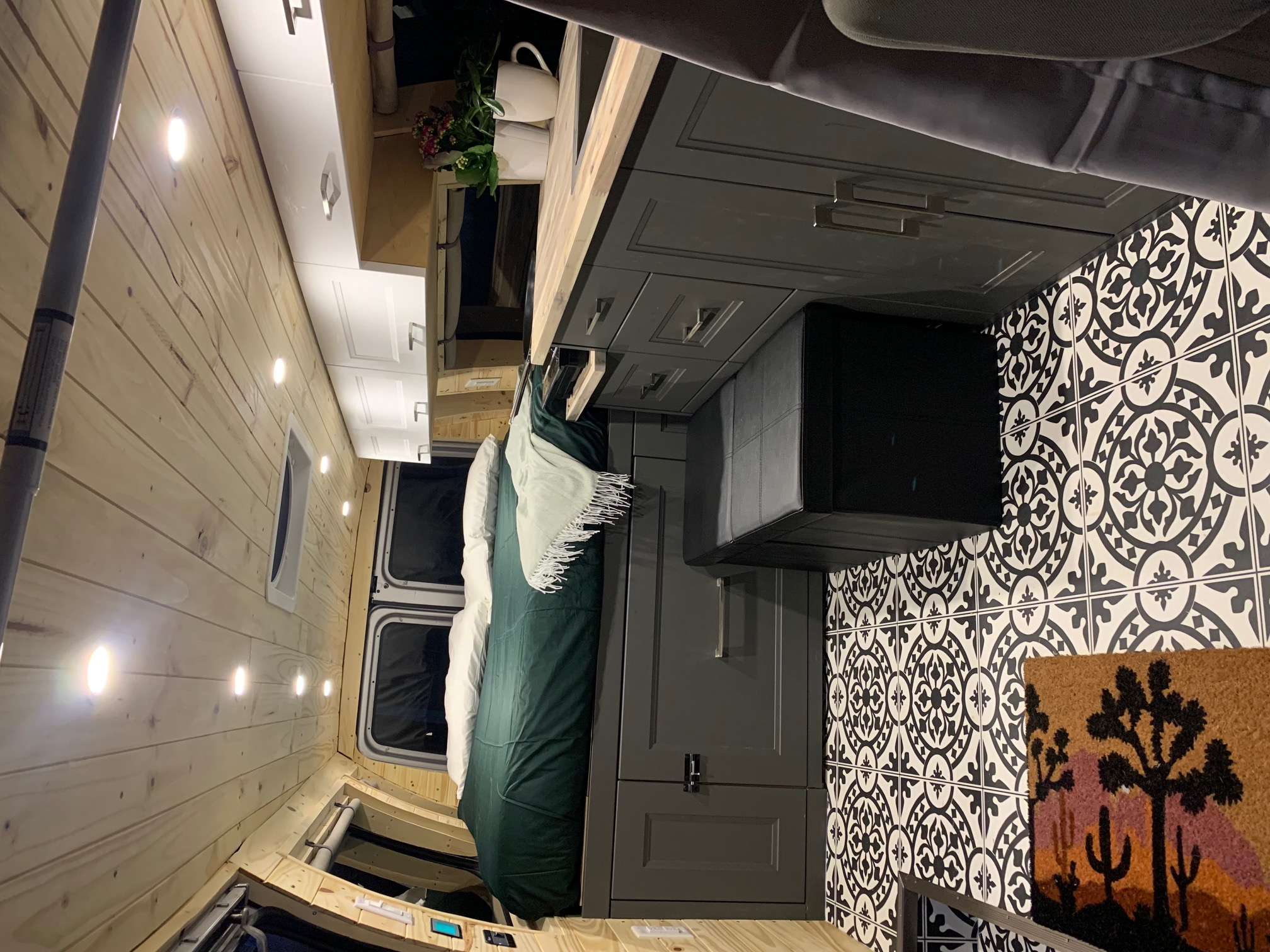 Spacious RV rental interior featuring light wood walls, dark gray cabinetry, a comfy bed, and eye-catching patterned floor tiles.. Ford E350 Box Van 2013
