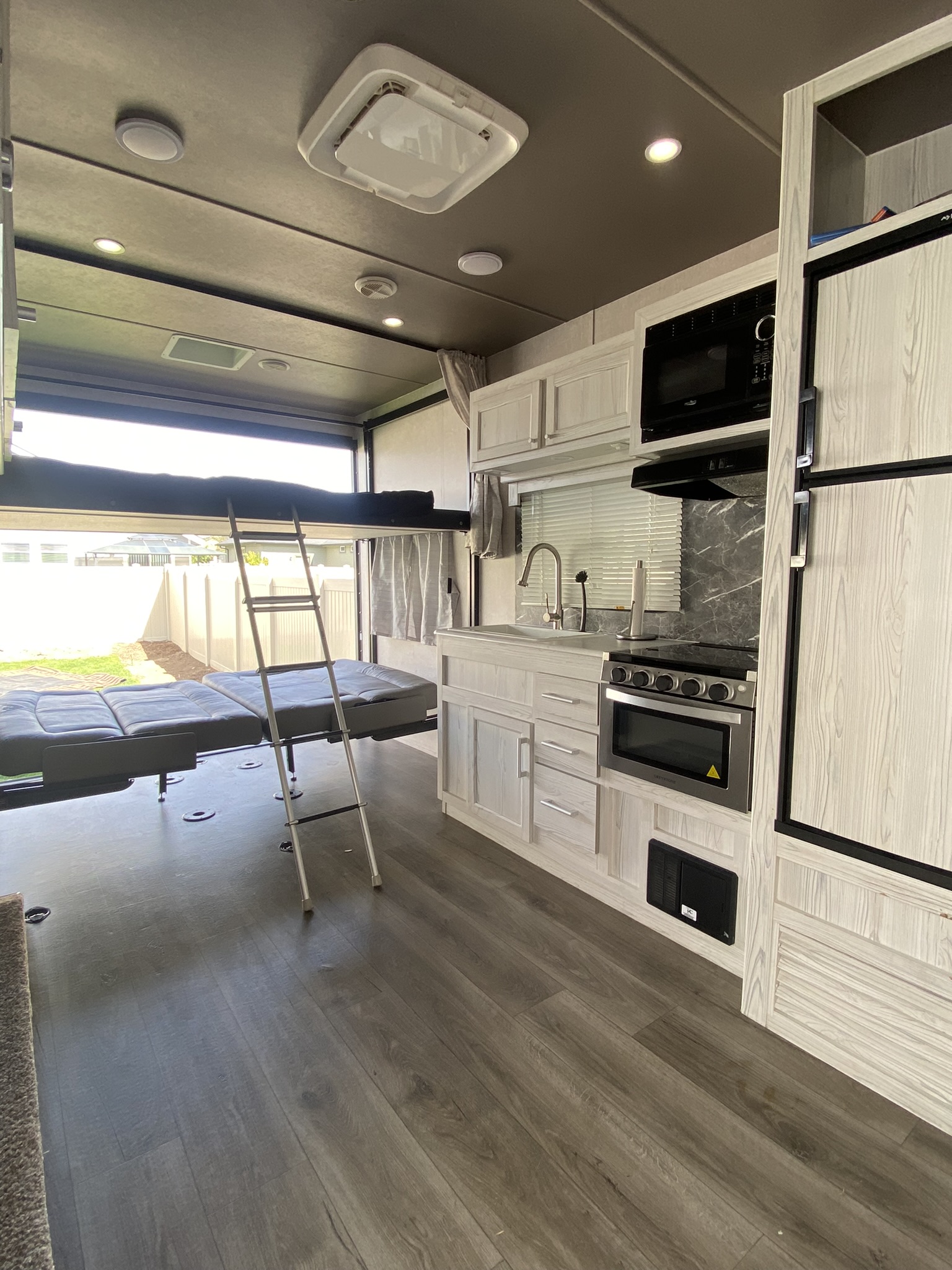 Modern RV rental interior with kitchen, oven, fridge, and multi-functional bed area with bunk and ladder.. Eclipse Recreational Vehicles Attitude 2021