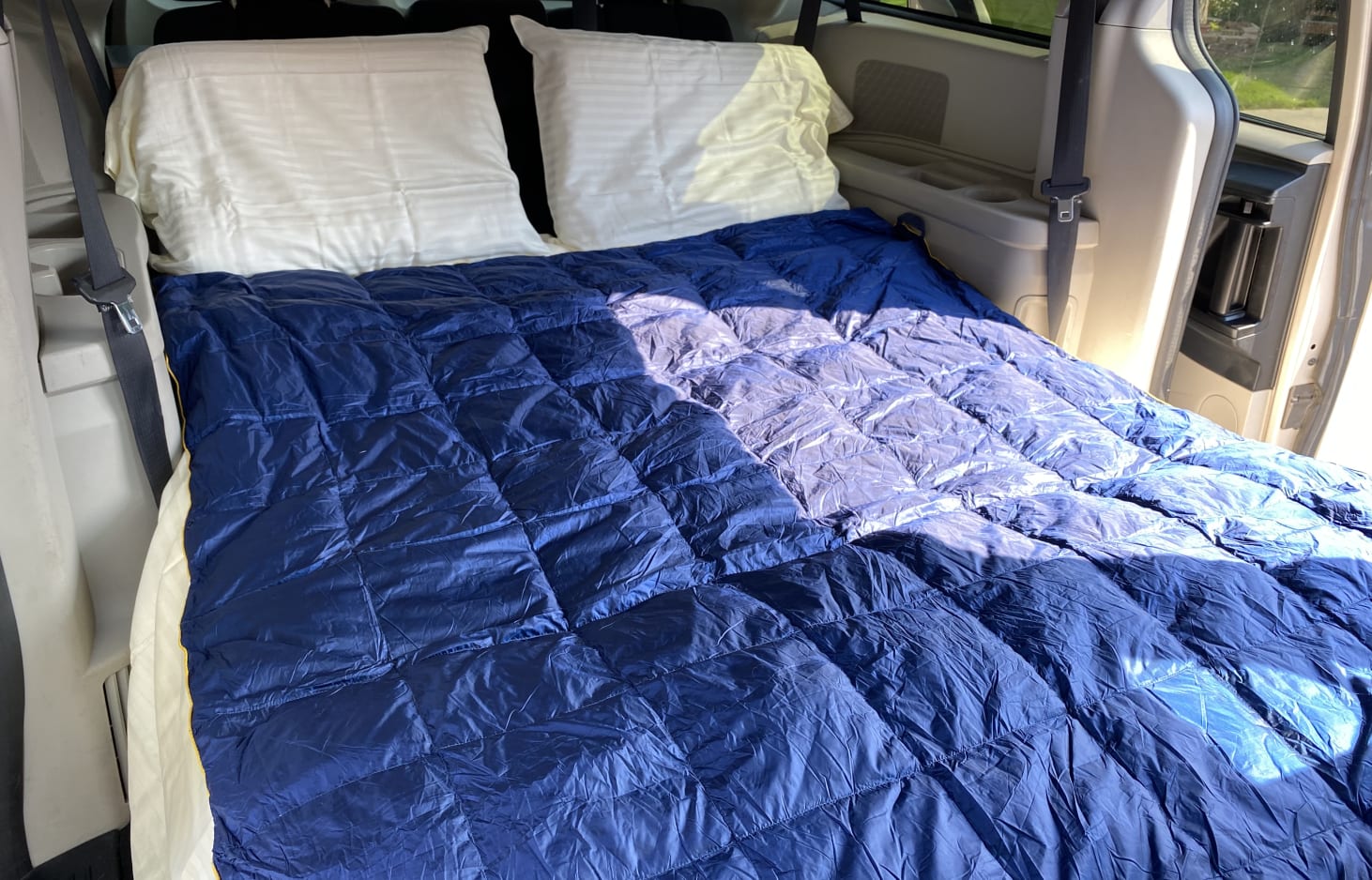 Comfy rv rental van bed: pillows & blue comforter transform this vehicle into a camping sleep setup.. Dodge Grand Caravan 2013