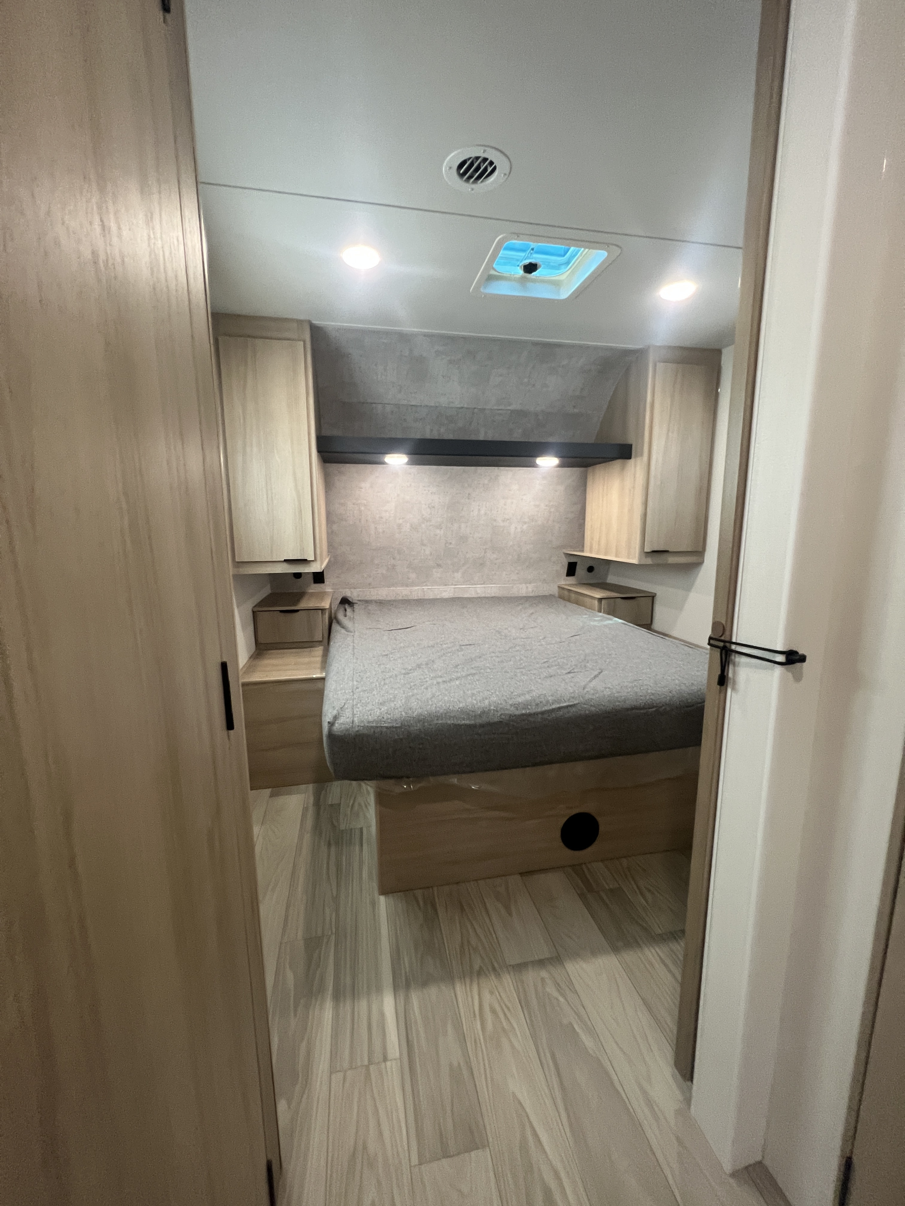 Modern RV rental bedroom featuring a comfortable bed, overhead storage, and ceiling lights. Ideal for travel trailer journeys.. Winnebago Minnie 2529RG 2023