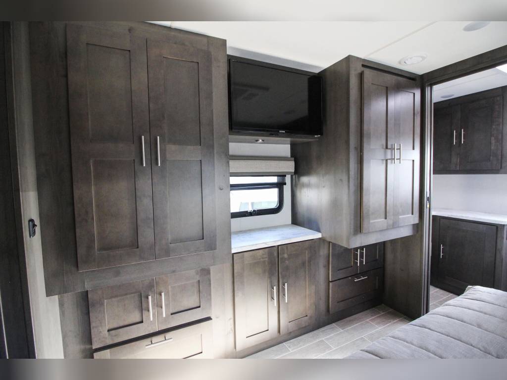RV rental bedroom interior: dark wood cabinetry, TV, and extensive storage optimize space for travel.. Forest River Georgetown 2023