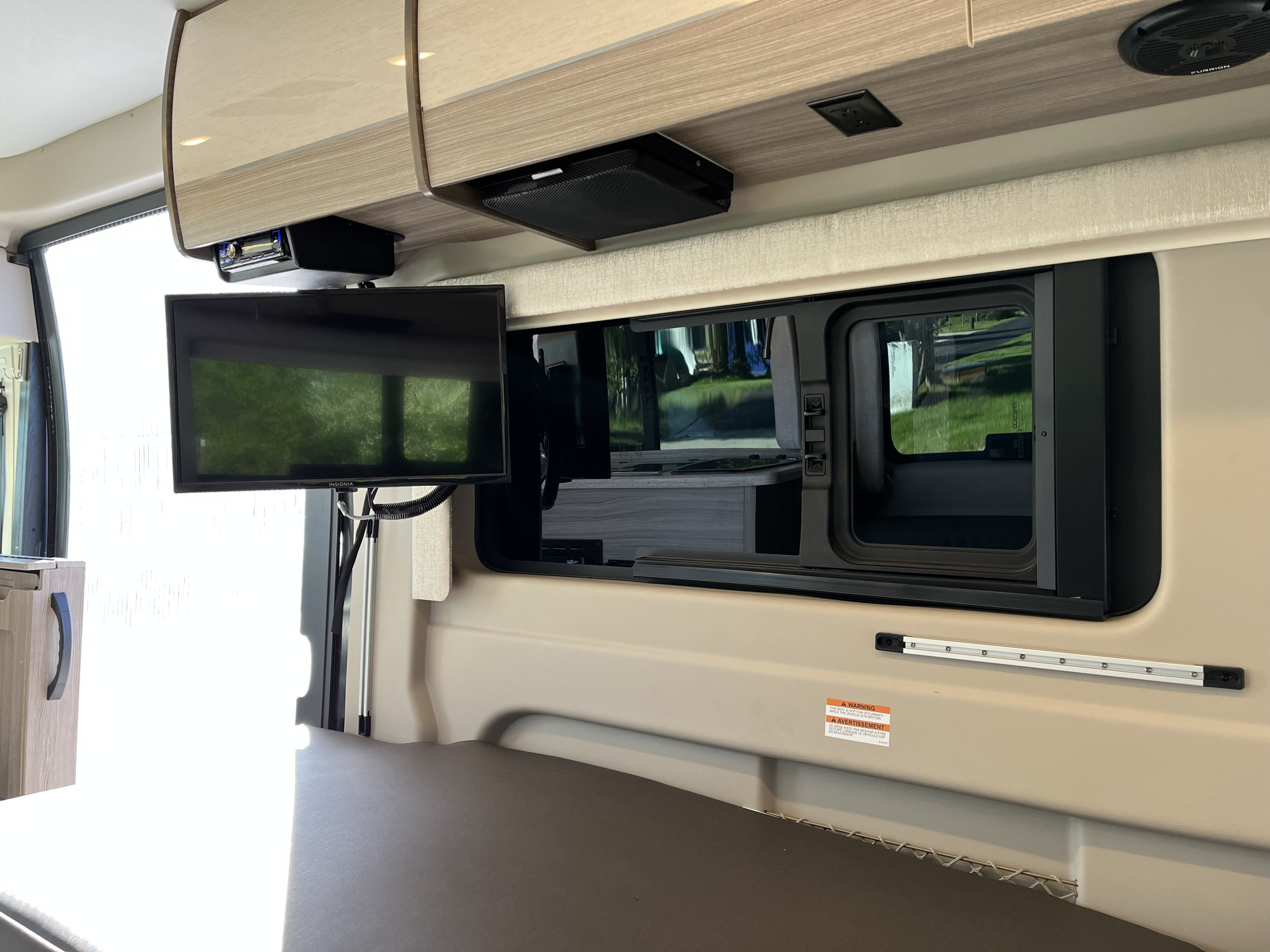 Modern rv rental interior with a wall-mounted TV, built-in stereo, and wide window perfect for scenic travel.. Jayco Swift 2022