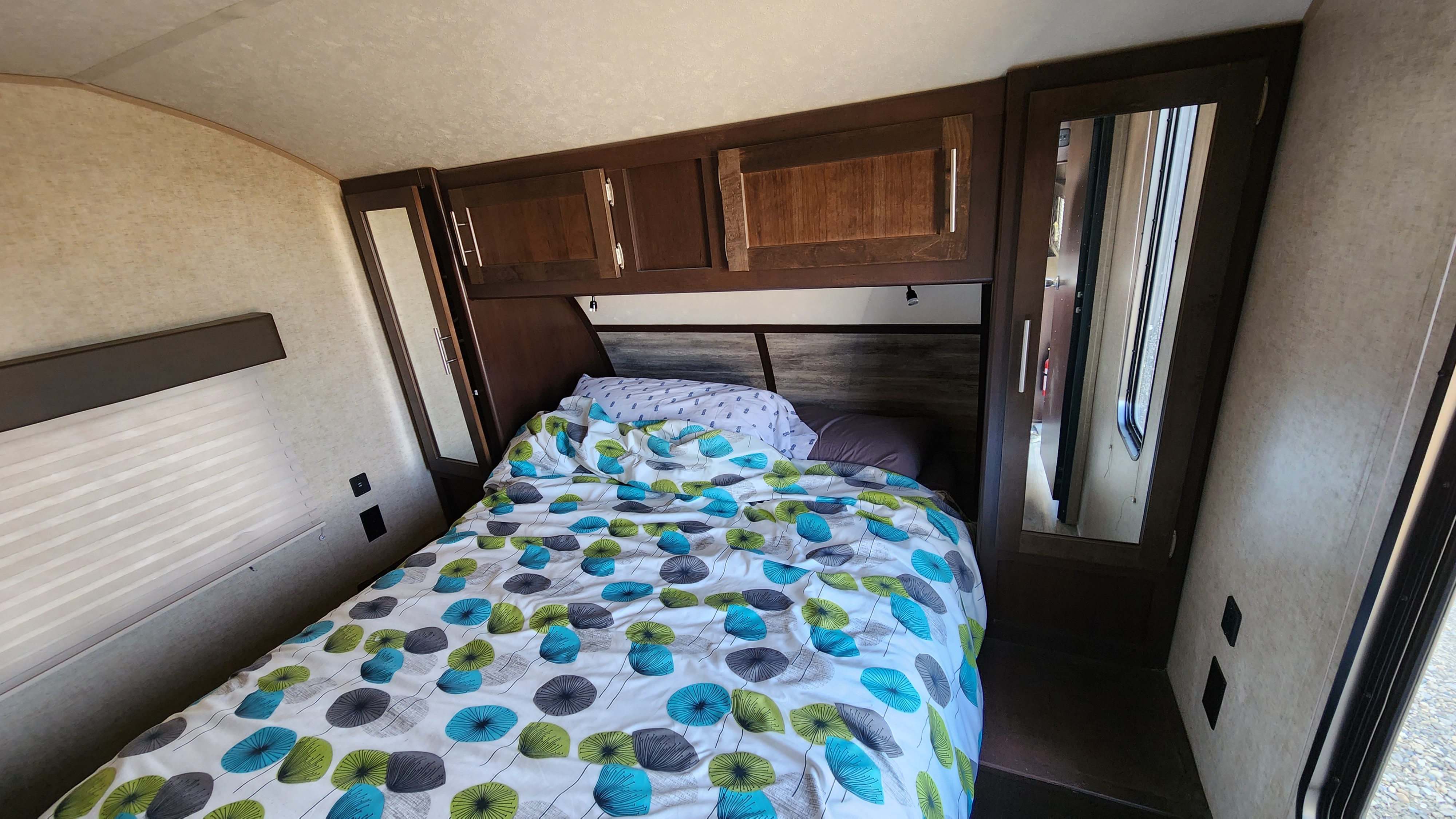 Experience comfort in this RV rental bedroom: cozy bed, overhead cabinets, and mirrored closets for your travels.. Forest River Cherokee 2018