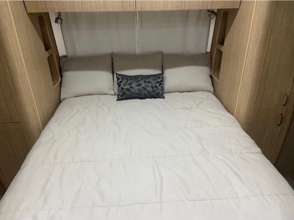 RV rental bedroom: A comfortable bed with white bedding, pillows, and functional built-in storage.. Airstream Flying Cloud 2019