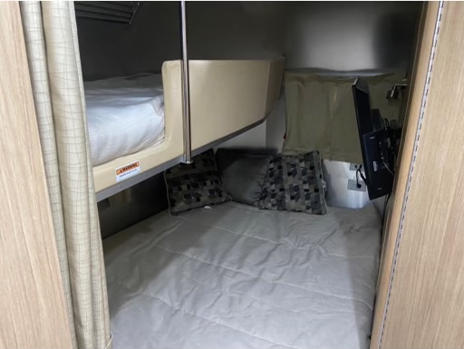 This **rv rental** offers a comfortable lower bed, an upper bunk, and a wall-mounted TV in its compact sleeping area.. Airstream Flying Cloud 2019