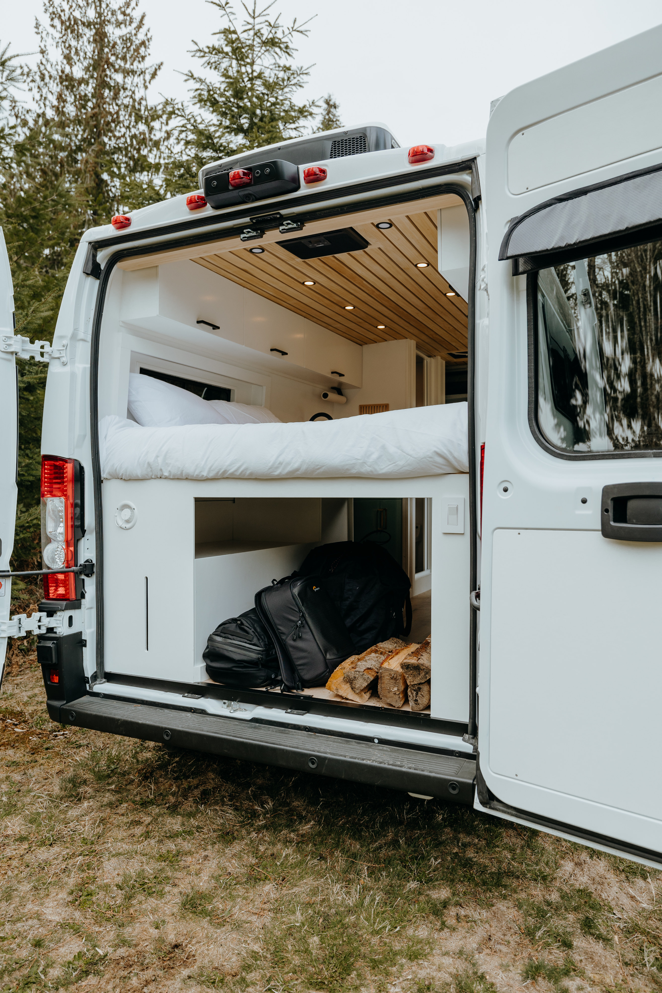 Spacious RV rental interior featuring a cozy bed, ample storage for travel gear & firewood. Perfect for adventure!. Ram Promaster 2500 2021