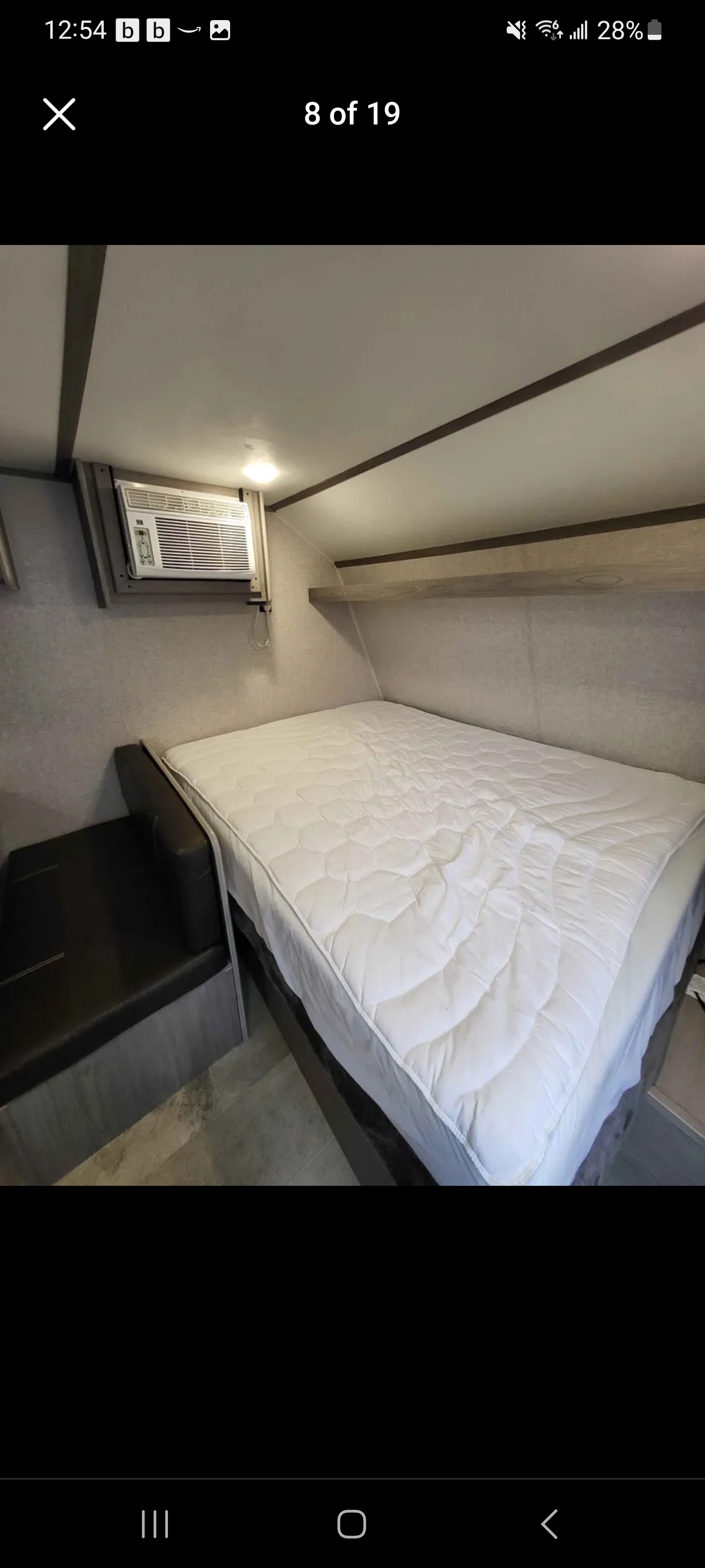 This cozy RV rental interior features a comfortable bed, an AC unit, and a small seating area.. Dutchmen Coleman Lantern LT 2022