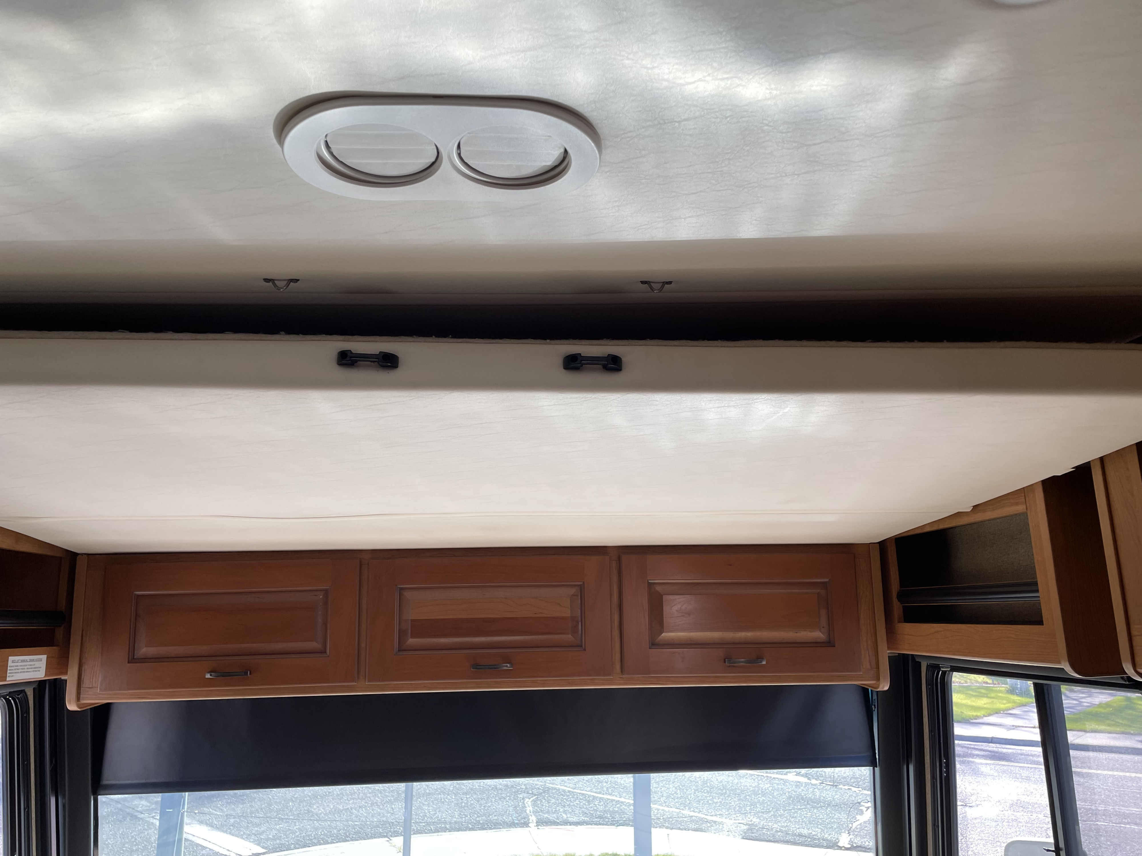 RV rental interior showing a drop-down bed, overhead cabinets, and ceiling vent. Provides extra sleeping and storage space.. Fleetwood Excursion 2015