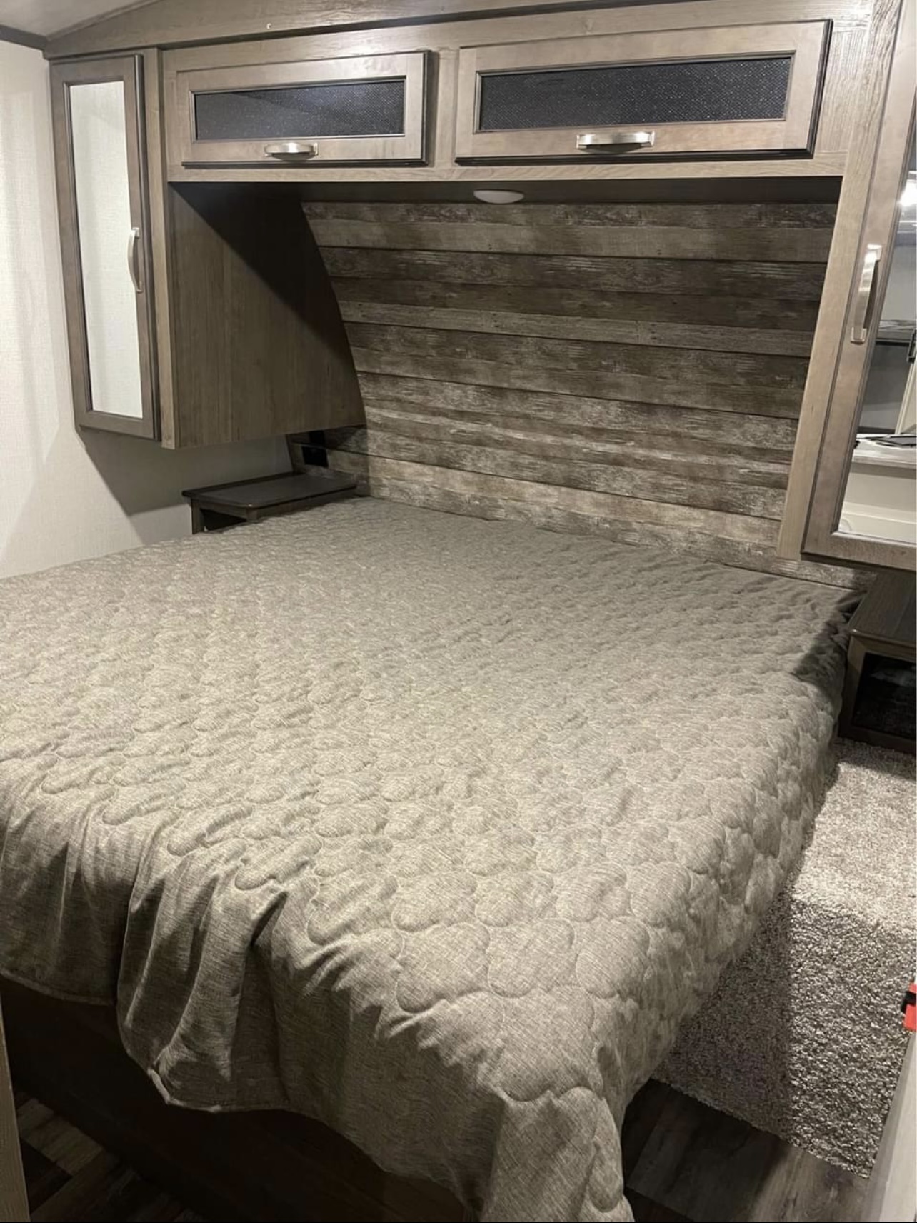 Inside an RV rental, a cozy bedroom with a quilted bed, wooden headboard, and functional overhead storage. Perfect for adventurers.. Keyston Cougar Half Ton 29BHSWE 2021
