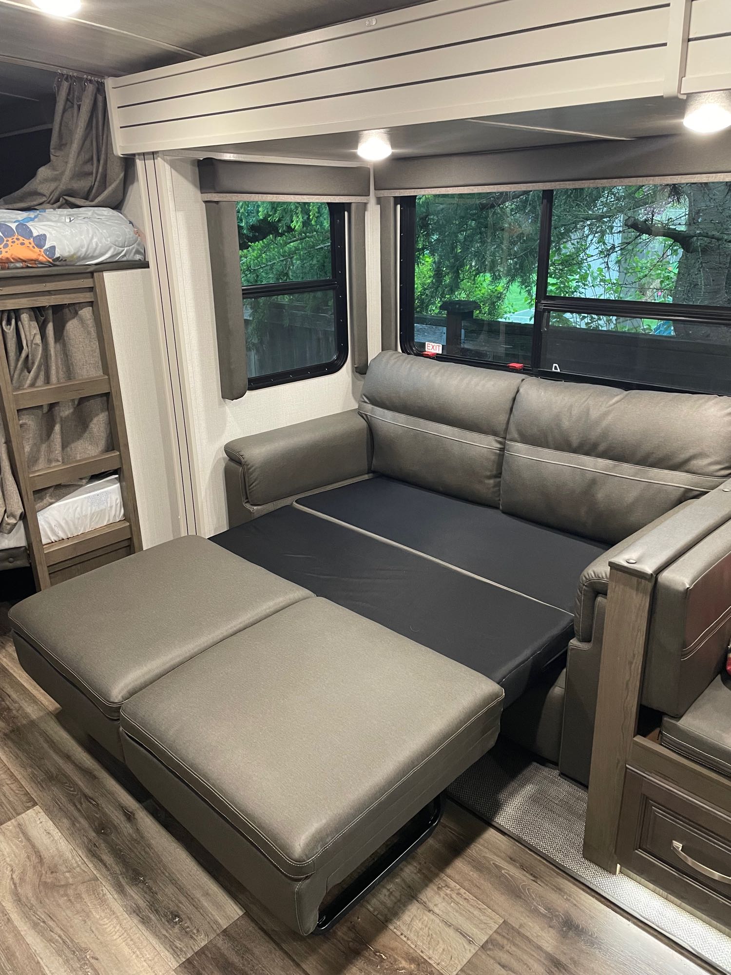 Inside an RV rental, a sofa converting to a bed optimizes the living space next to bunk beds and large windows.. Keyston Cougar Half Ton 29BHSWE 2021