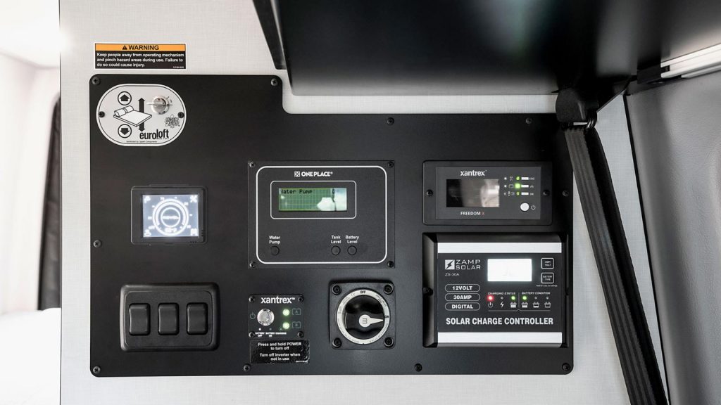 RV rental interior control panel: monitor for solar, power, and water, plus Eurolift bed switch.. Winnebago Revel 2022