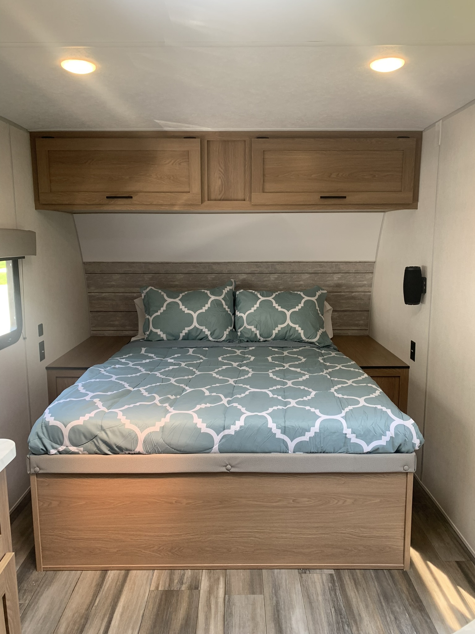 Cozy RV rental bedroom features a comfy bed with patterned bedding, overhead storage, and wood finishes, perfect for your journey.. Forest River Other 2023