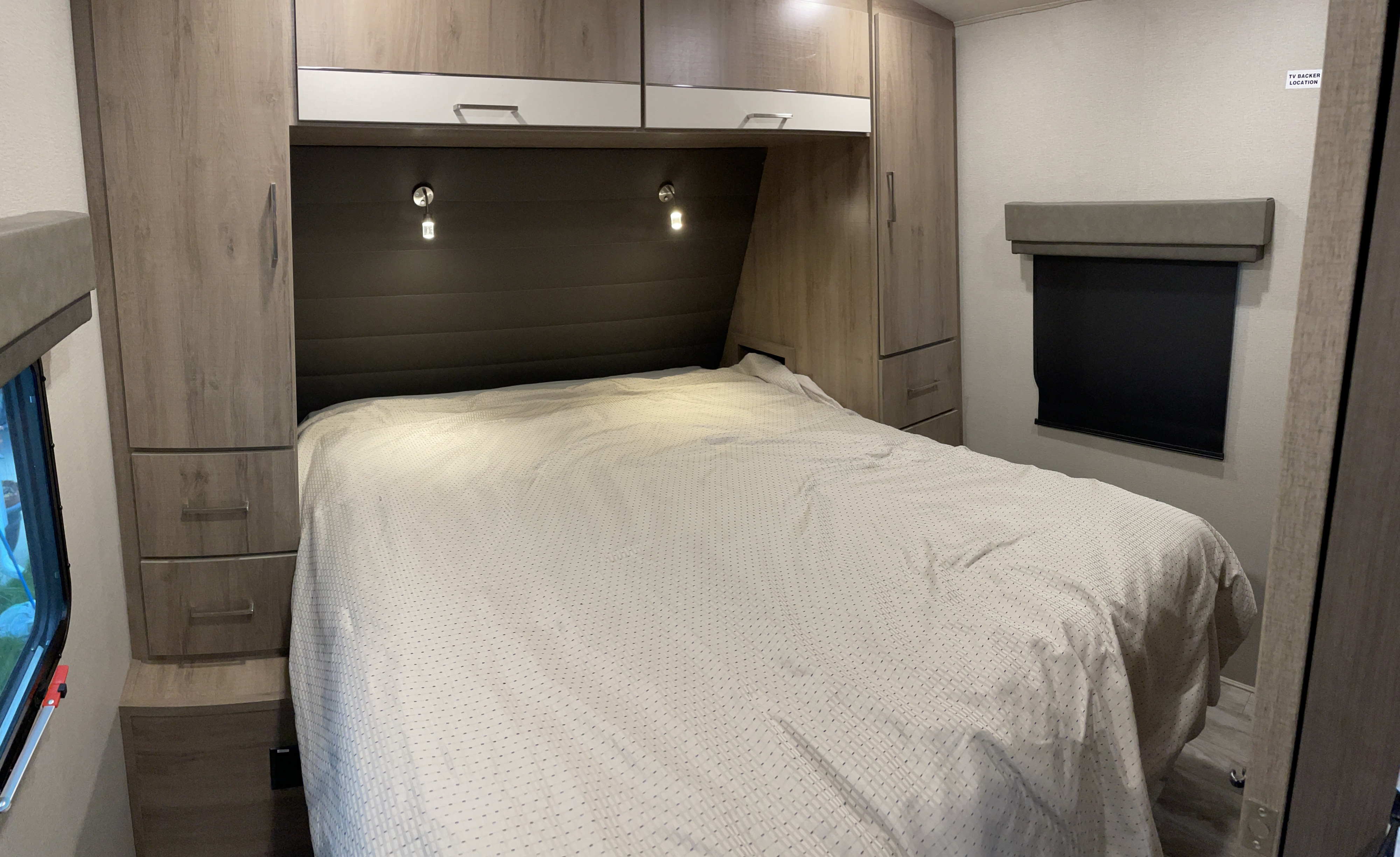 Cozy RV rental bedroom with bed, overhead cabinets, and bedside lights.. Grand Design Imagine 2022
