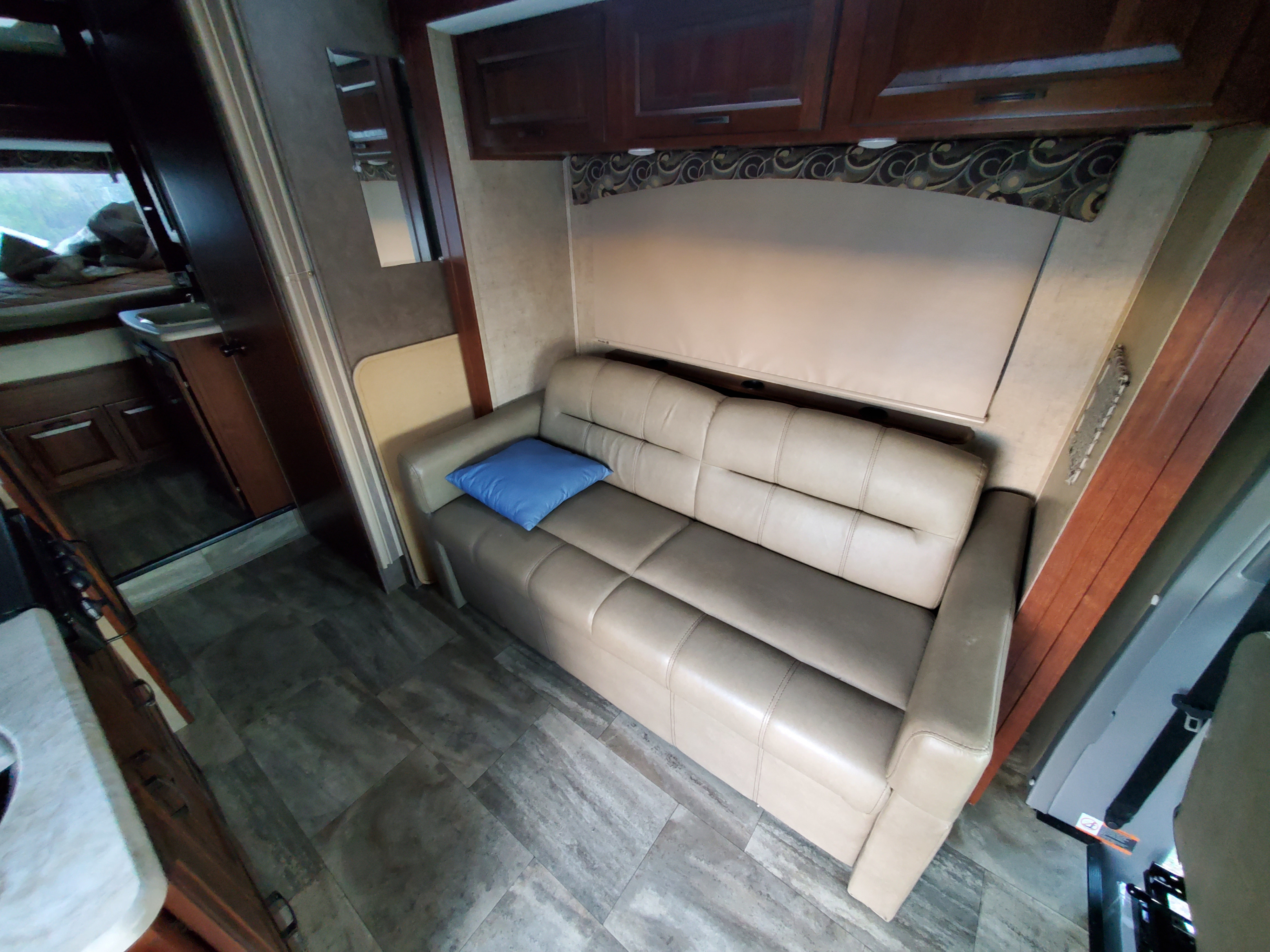 Inside this RV rental: a plush living area with a tan sofa, wood cabinets, and an adjacent bath. Modern, cozy camper life.. Forest River Sunseeker 2016