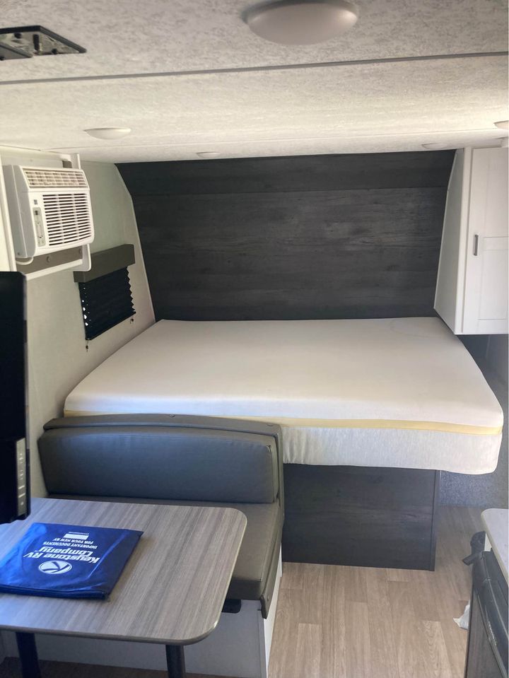 Cozy RV rental interior showing a bed, dinette, and AC unit. Perfect for travel adventures!. Keystone RV Hideout 2022