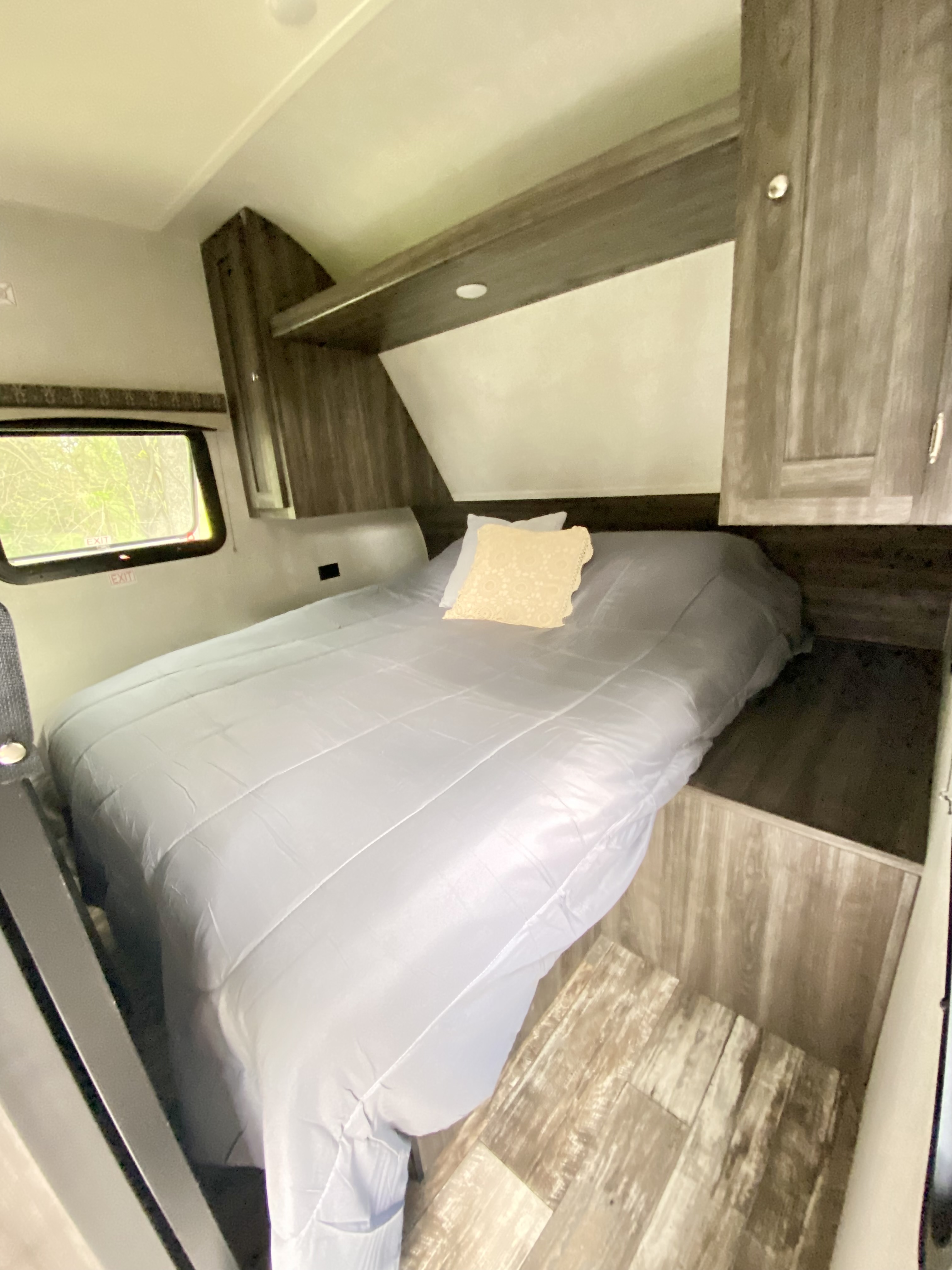 Cozy RV rental bedroom interior with a neatly made bed, overhead storage, and window, perfect for travel trailer adventures.. Starcraft Autumn Ridge Outfitter 2020