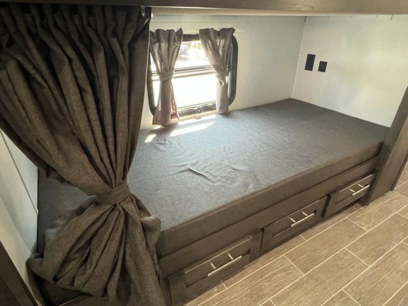 Cozy RV rental bunk bed with convenient storage drawers and a window view, ideal for family travel.. Forest River Georgetown GT5 2023