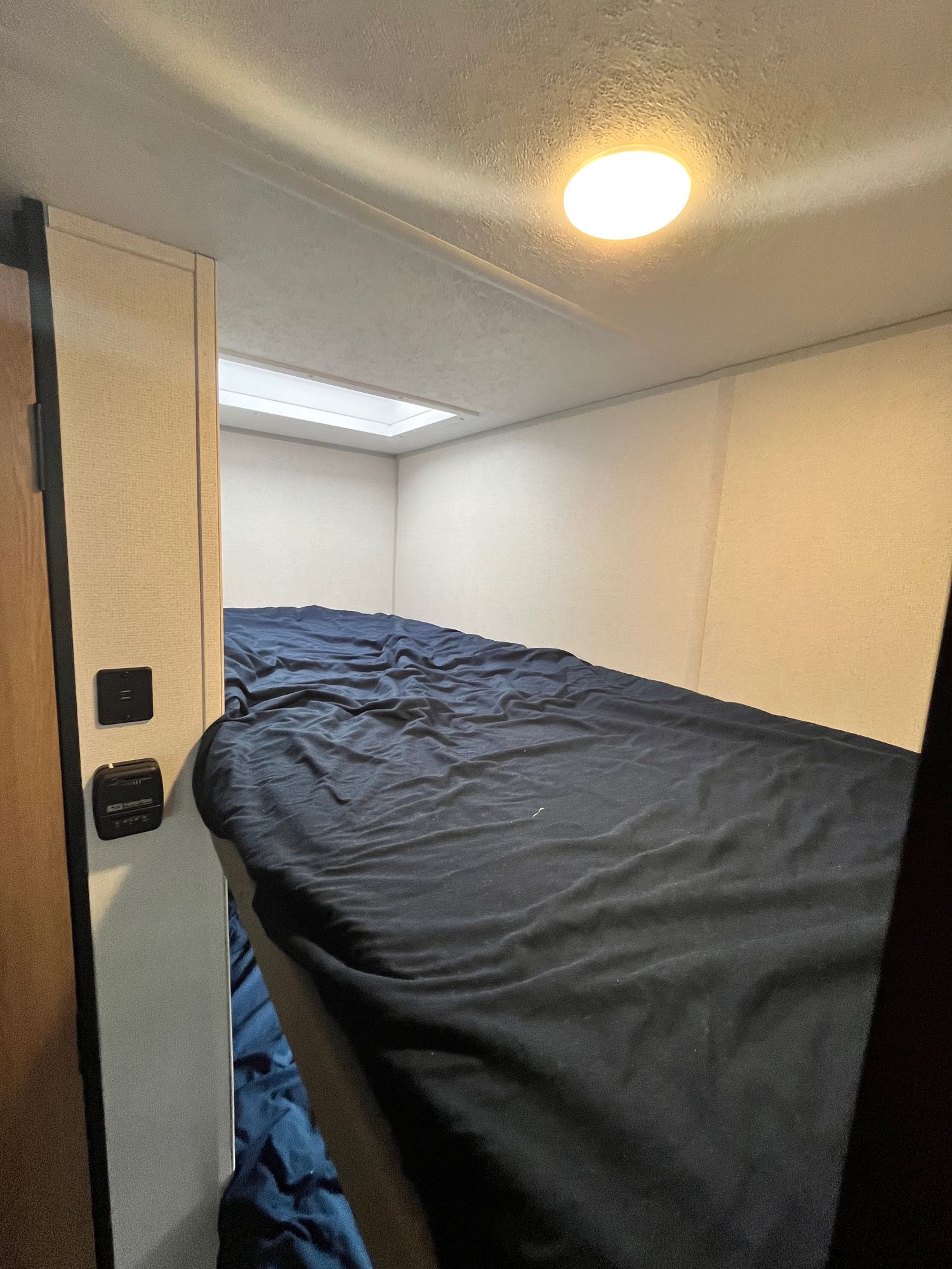Cozy RV rental bunk bed setup with ceiling light & skylight. Perfect for a compact sleep space.. Avenger LT 2022