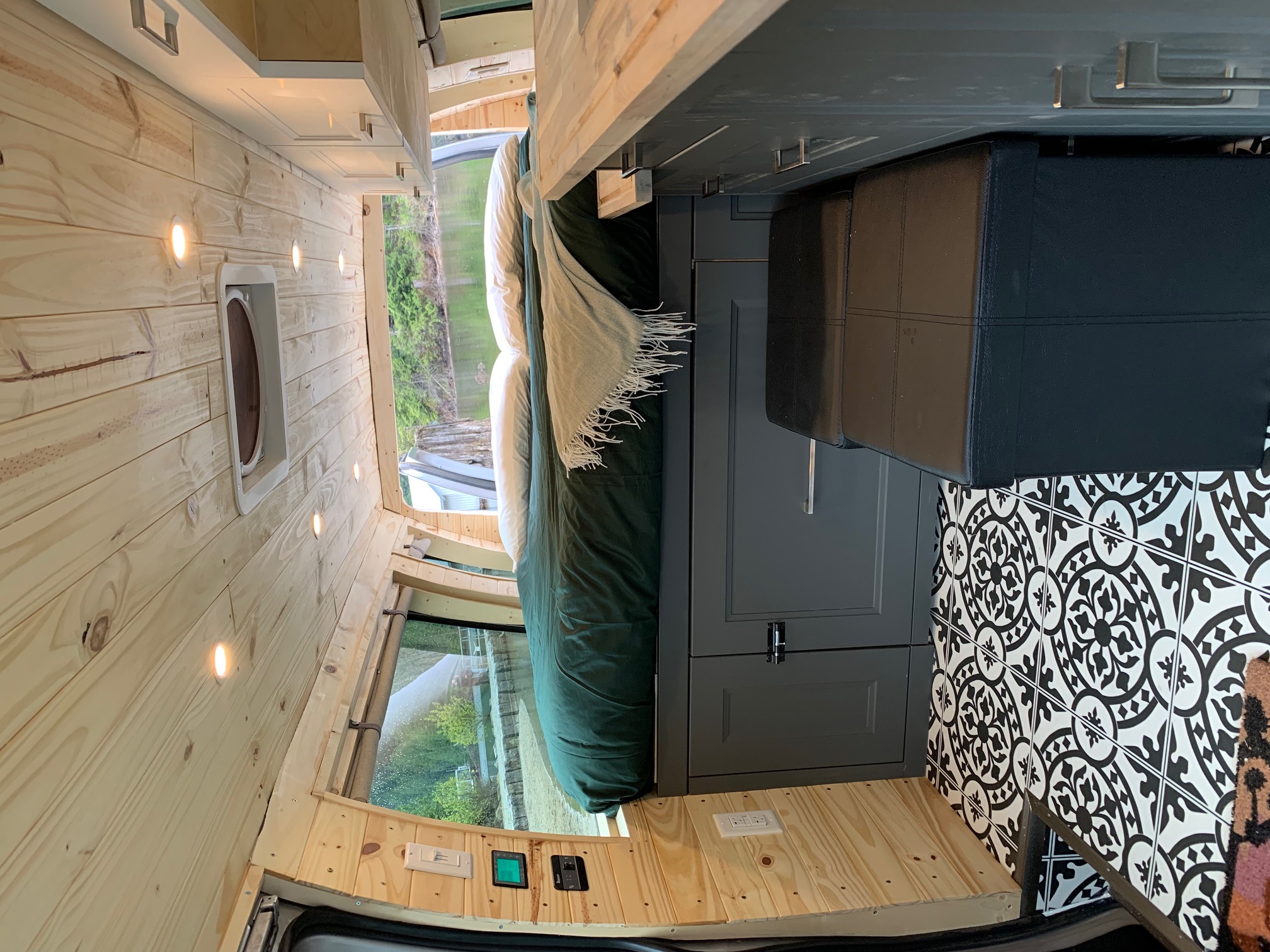 Experience the cozy interior of this RV rental, featuring warm wood paneling, a comfy bed, and a modern kitchen.. Ford E350 Box Van 2013