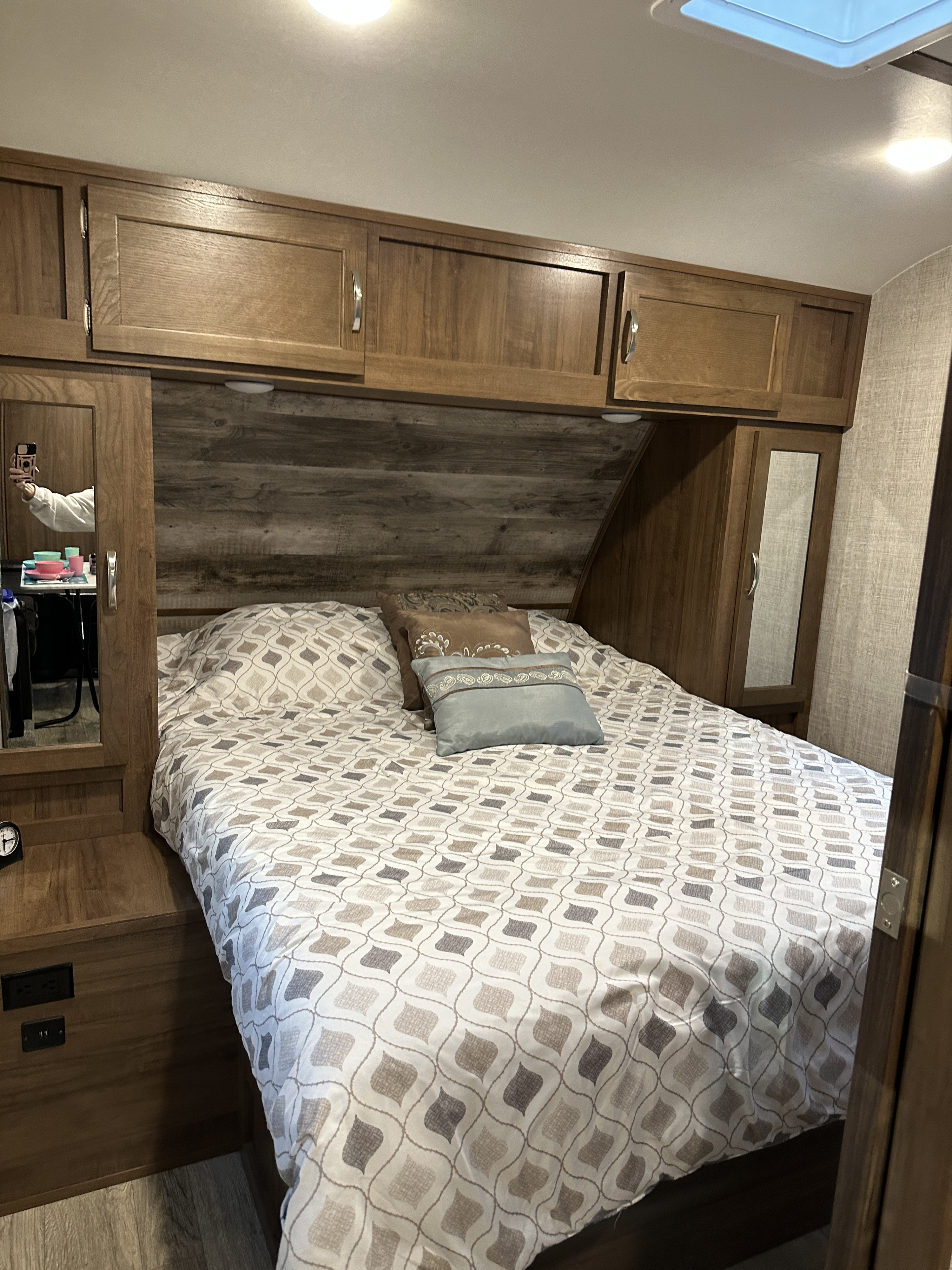 Cozy RV rental bedroom with patterned bedding, overhead cabinets, and built-in amenities, ready for your next adventure.. Gulf Stream Envision 2020
