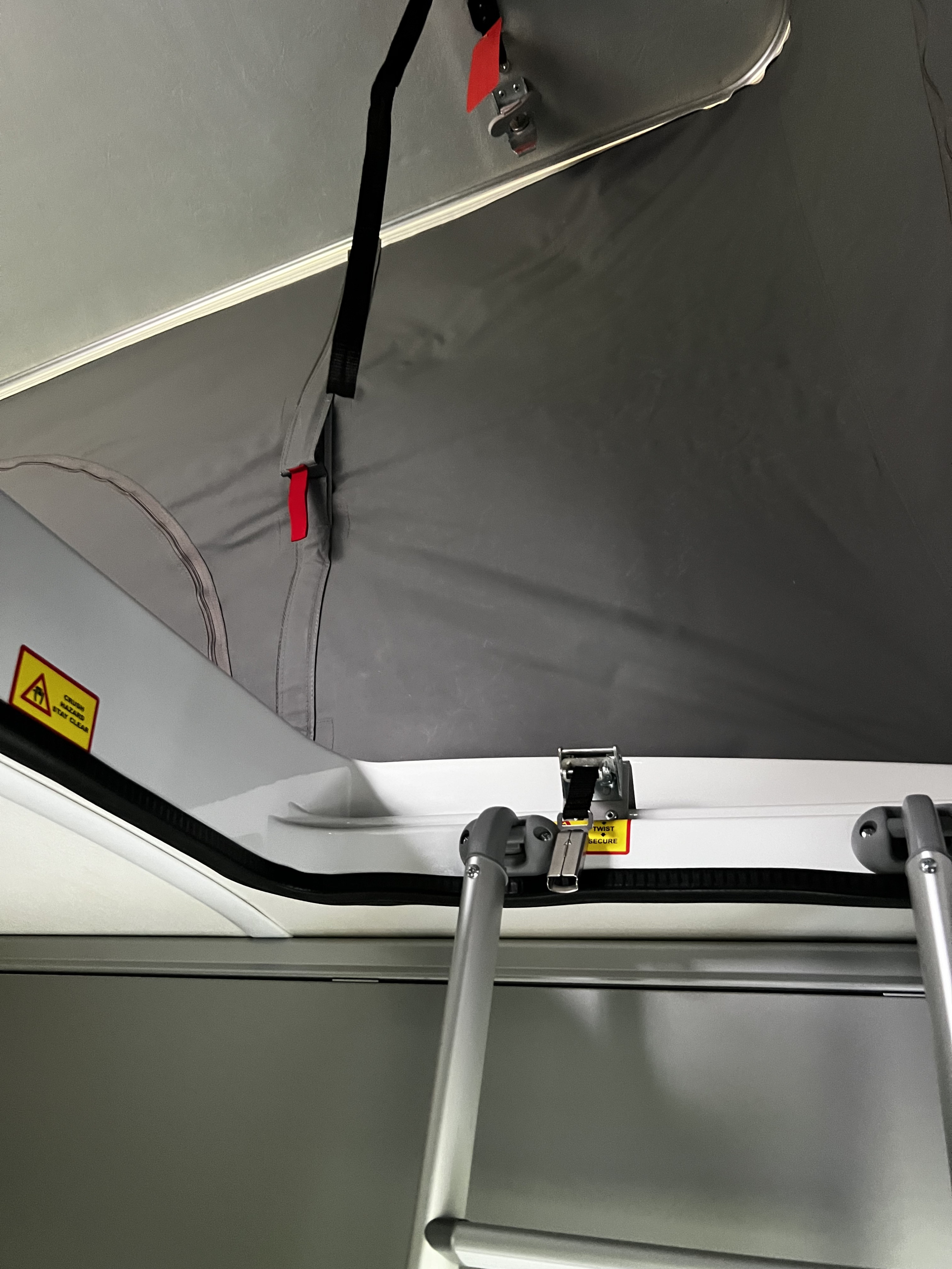 RV rental: Pop-top access with ladder, fabric interior walls, and safety warnings are visible.. Winnebago Solis 2023